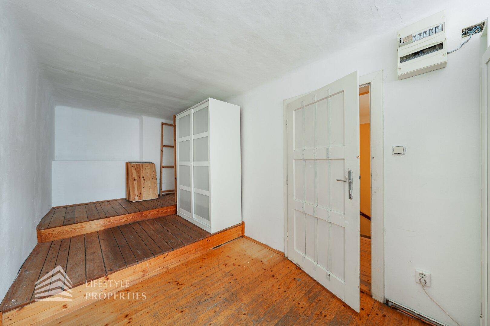 Kleiner Raum mit Holzboden und weißem Schrank, ideal als Abstellraum oder Gästezimmer.