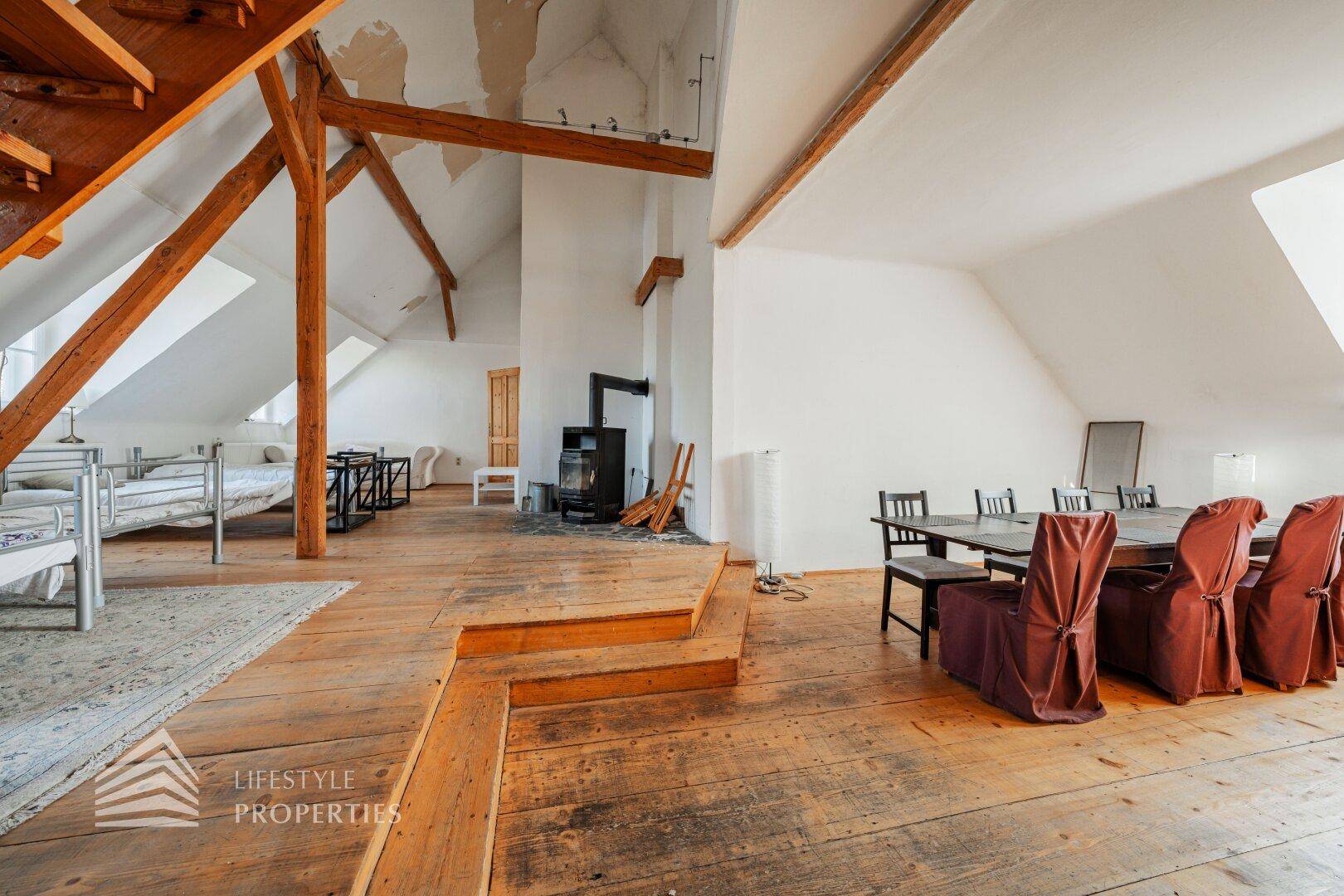 Helles Schlafzimmer im Dachgeschoss mit Holzdielenboden, Dachschrägen und Fenster.