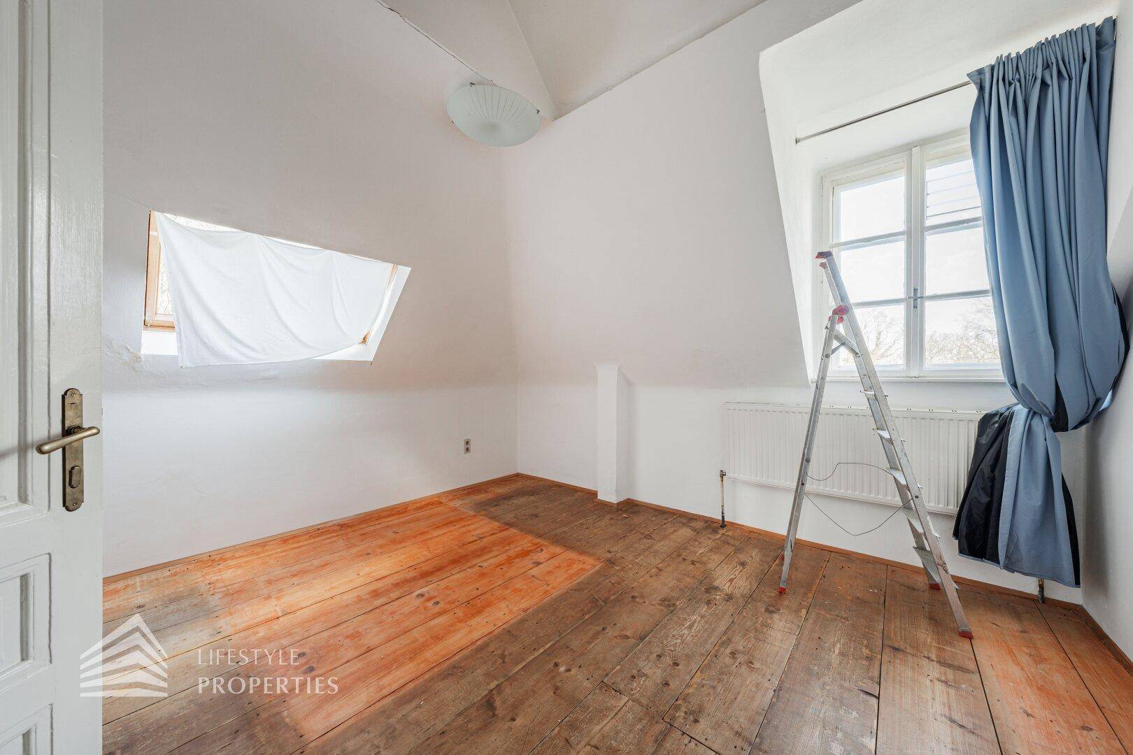 Badezimmer im Dachgeschoss mit Badewanne, Dusche, weißen Fliesen und Dachfenster.