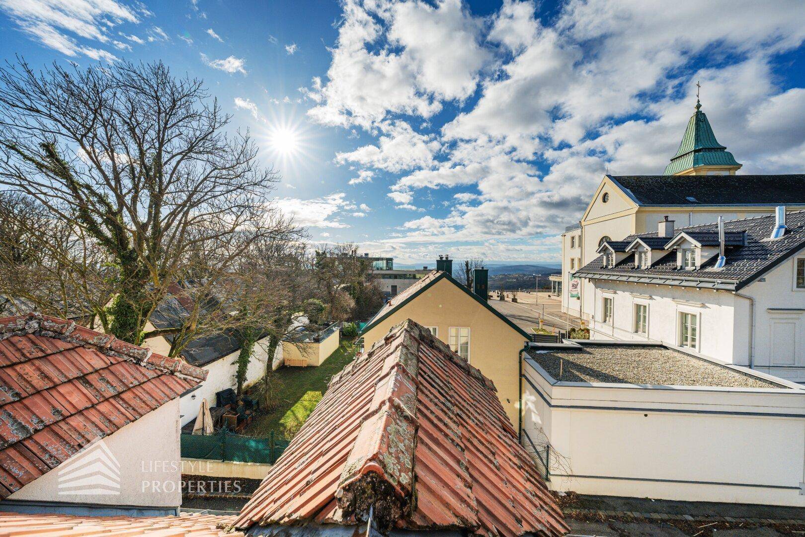 Panoramablick über die Dächer der Stadt und die umliegende Landschaft unter bewölktem Himmel.