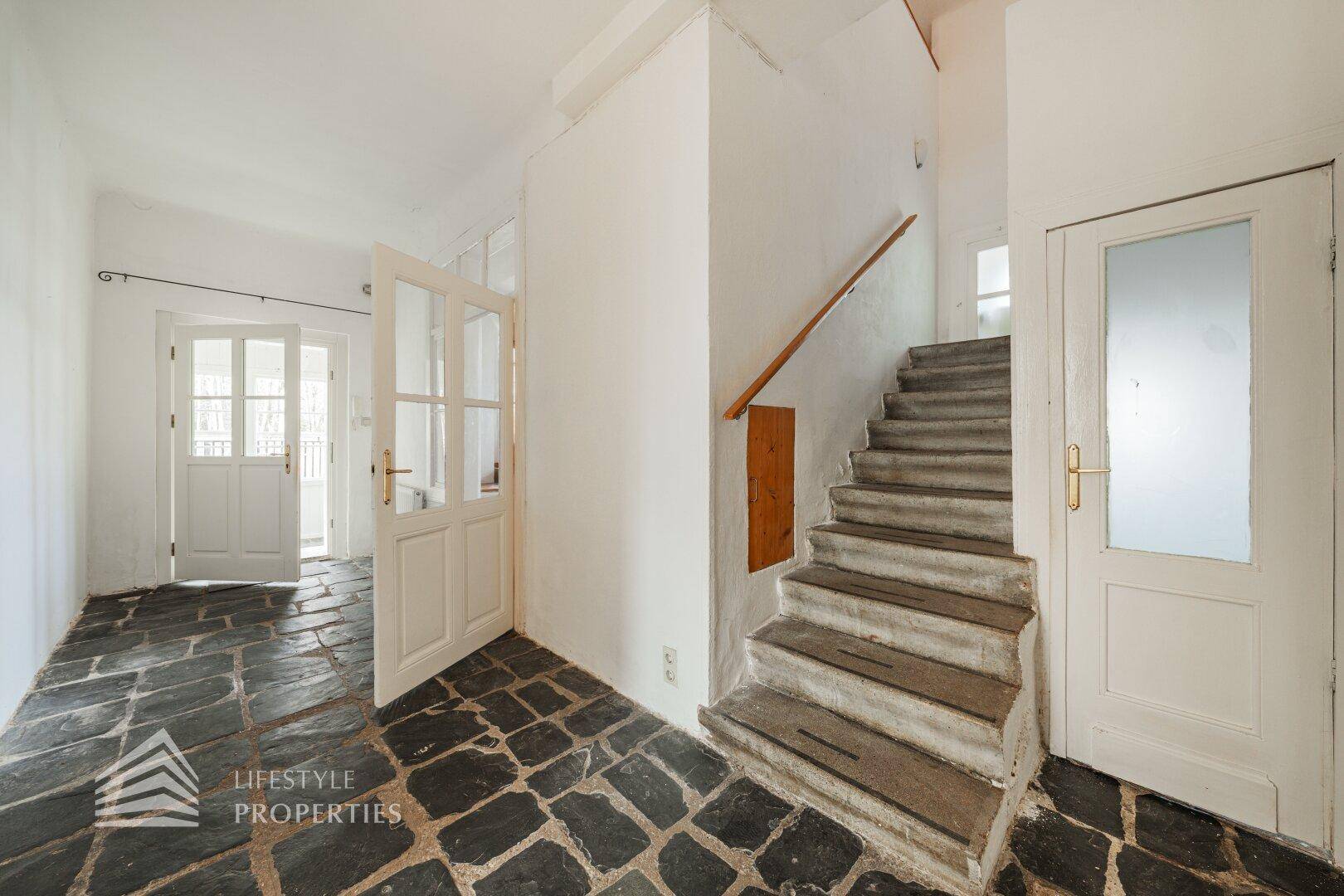 Helles Zimmer mit Holzdielenboden, weiß gestrichenen Wänden und großem Fenster.