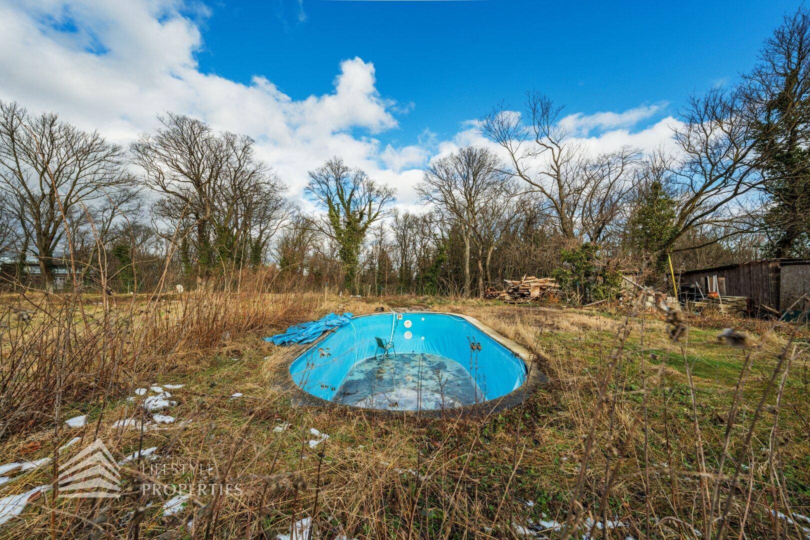 Gartenbereich mit einem eingelassenen Pool und Blick auf das historische Gebäude.
