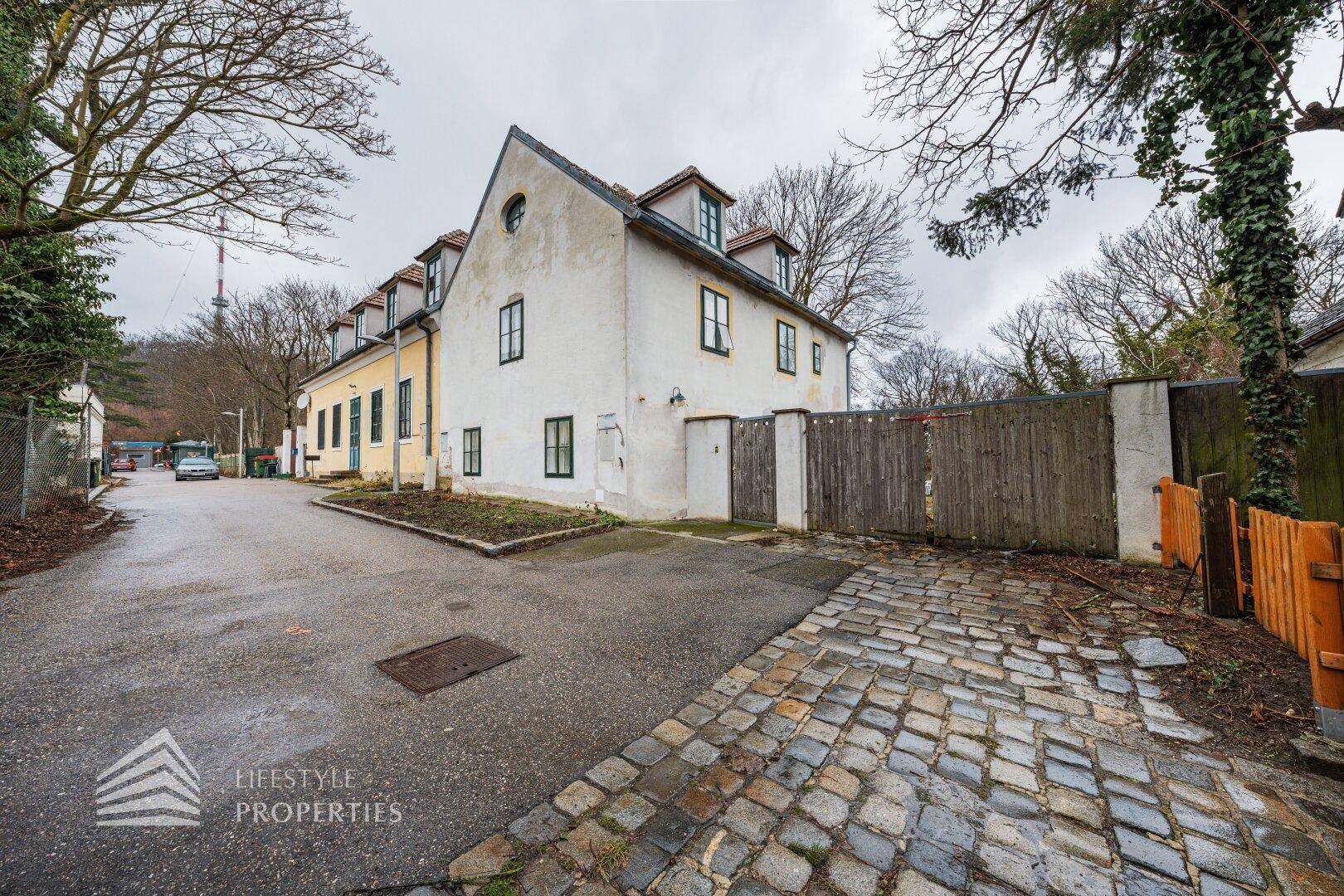 Historisches Gebäude mit gelber Fassade und großem Holztor an einer Straße.