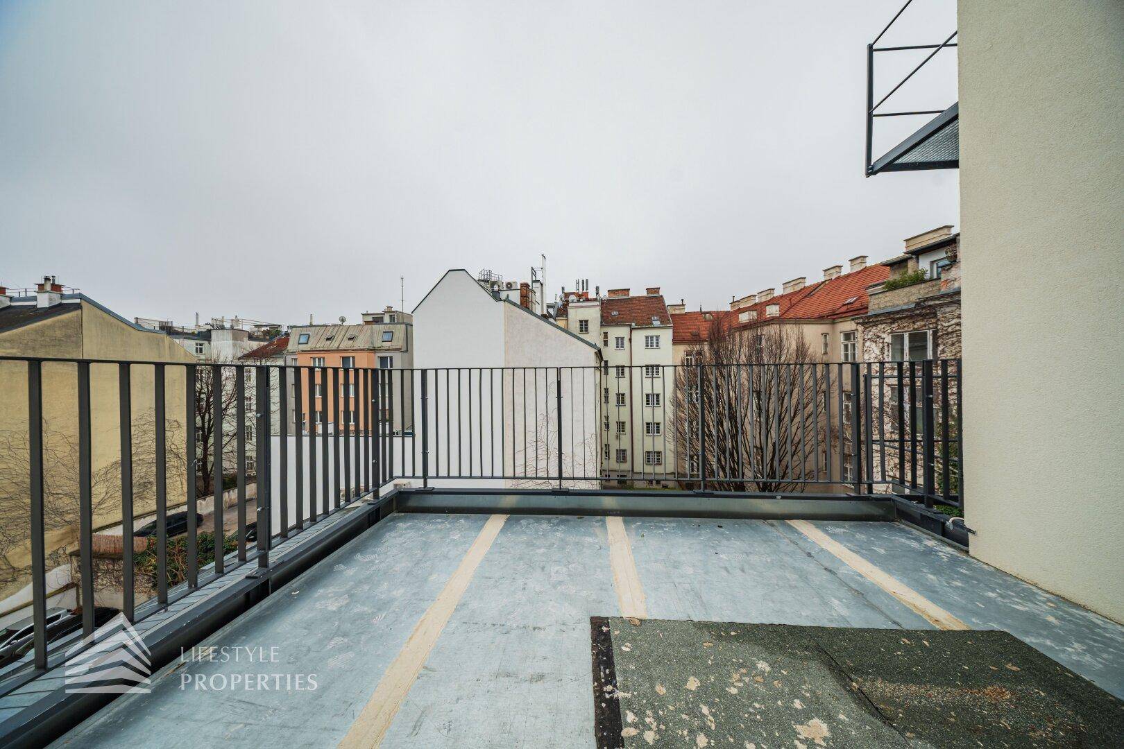 Weitläufige Terrasse mit Blick über die Dächer der Stadt und umliegende Gebäude.