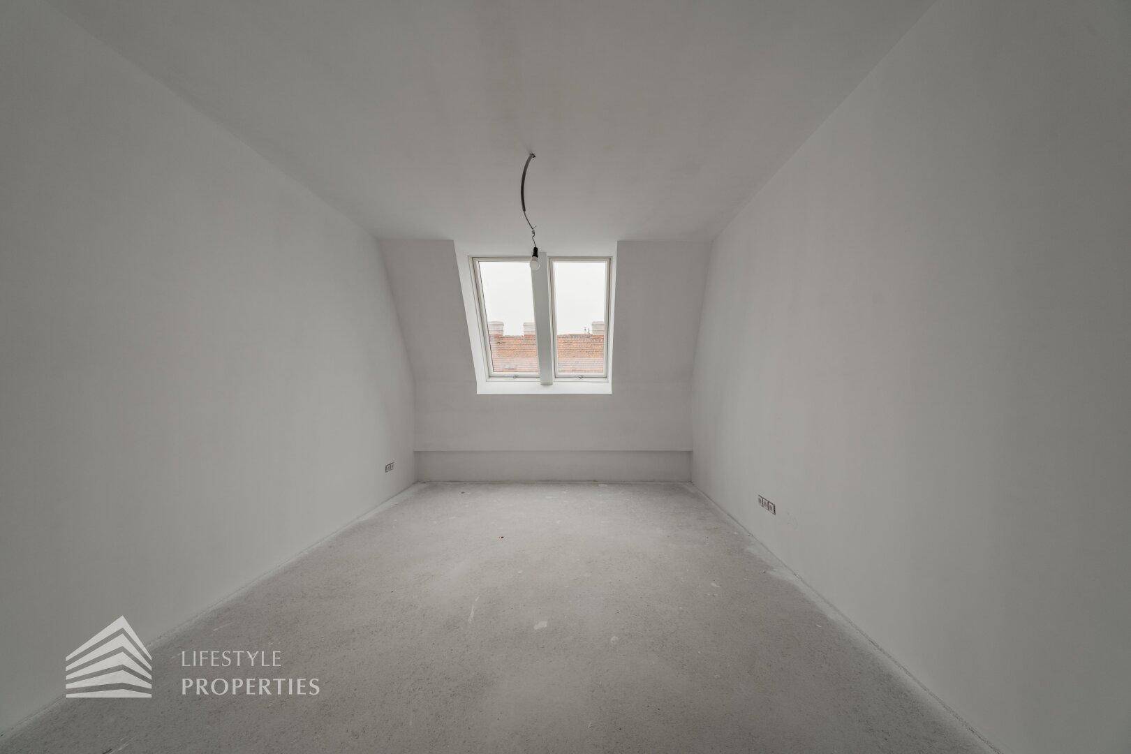 Heller Raum im Rohbau mit Dachschräge und zwei Dachfenstern, ideal als Schlafzimmer.