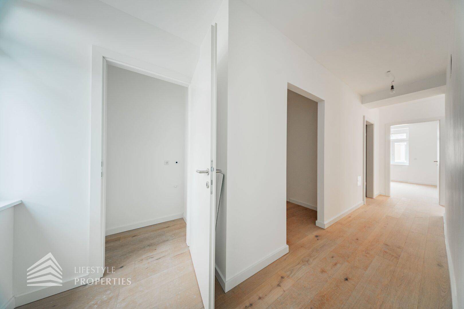 Heller Flur mit Holzboden und mehreren Türen, der verschiedene Räume verbindet.