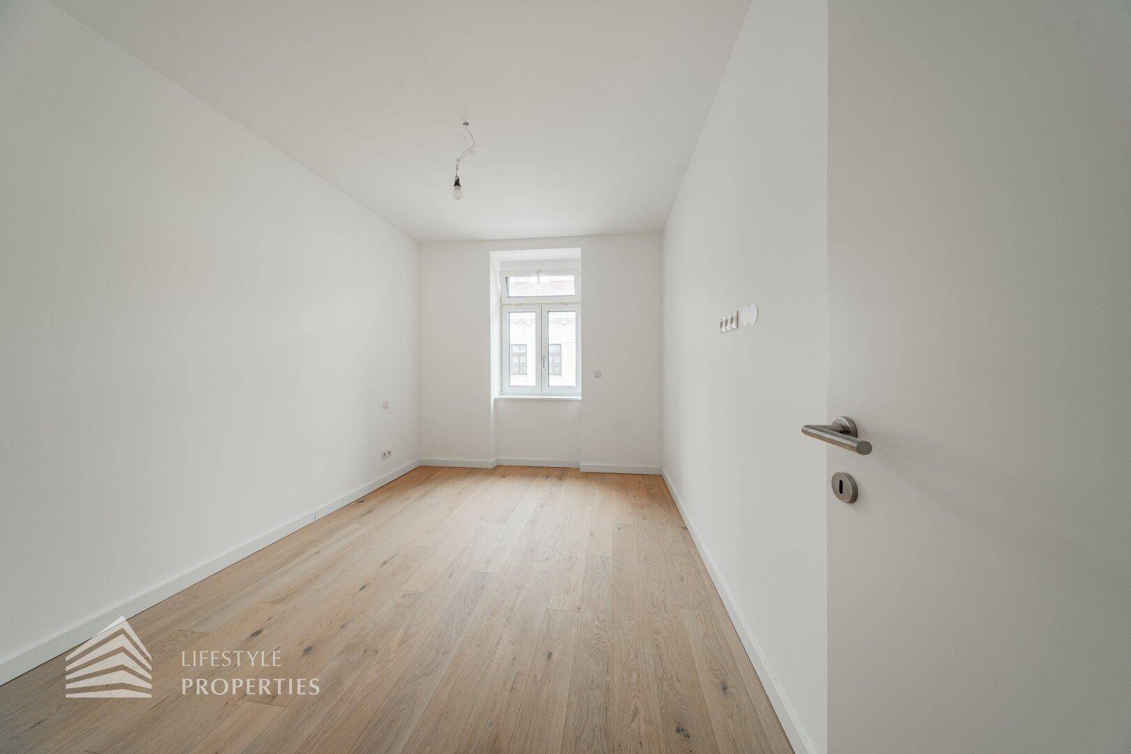 Leeres Zimmer mit Parkettboden und einem Fenster, bietet viel Potenzial für neue Bewohner.