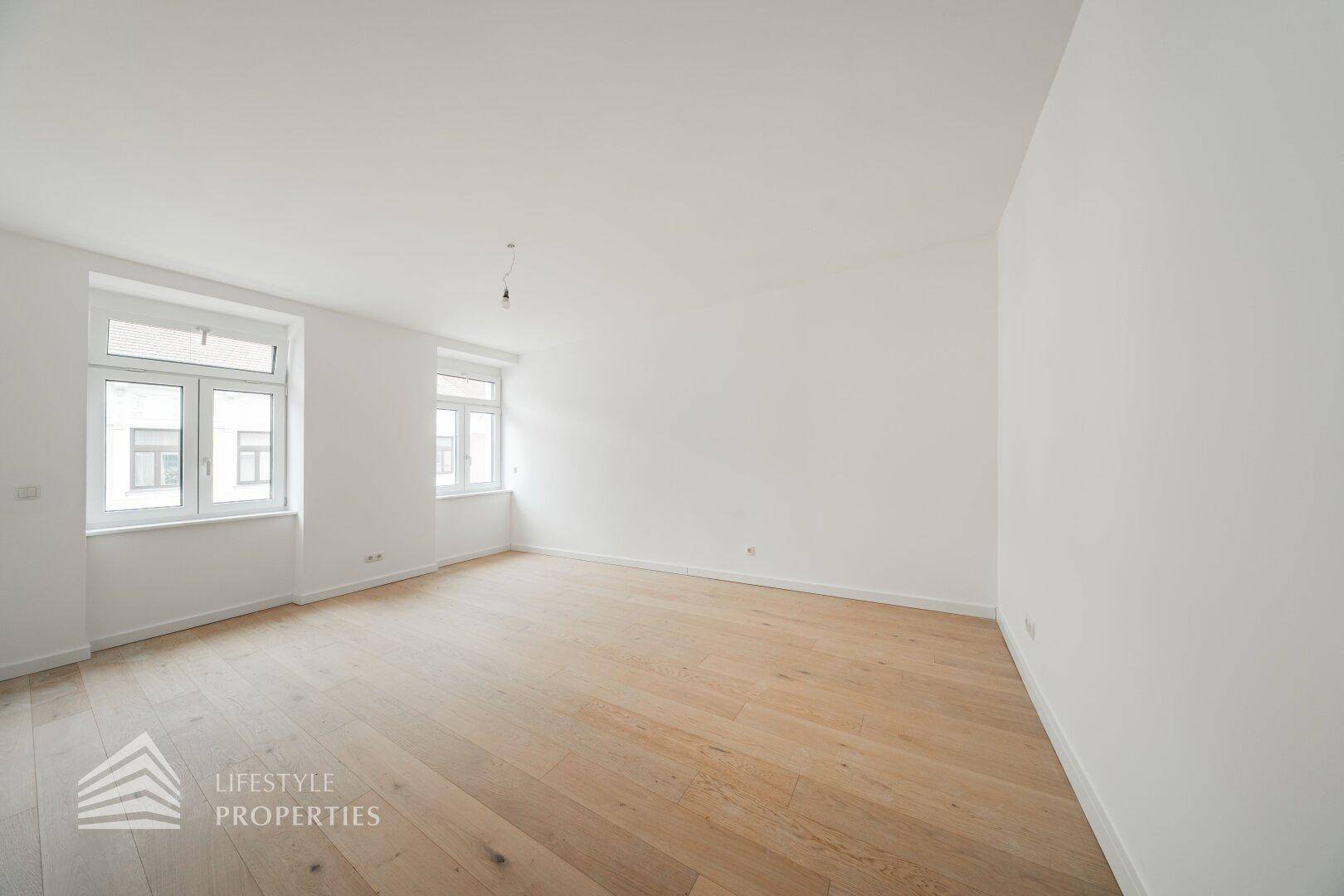 Geräumiges, helles Zimmer mit Holzboden und weißen Wänden, ideal für vielfältige Nutzung.