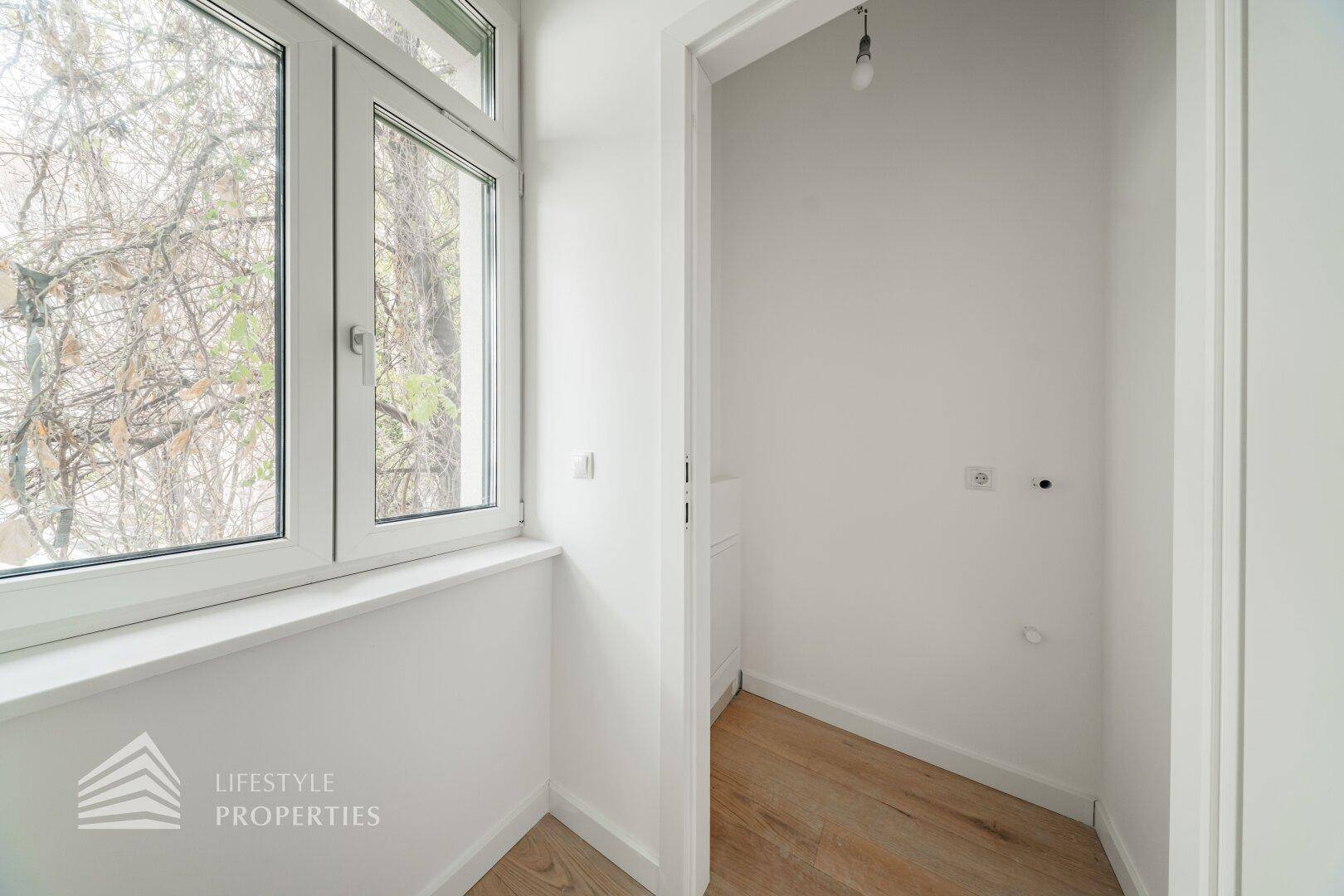 Kleiner Raum mit Fenster und Holzboden, ideal als Abstellraum oder für Haushaltsgeräte.