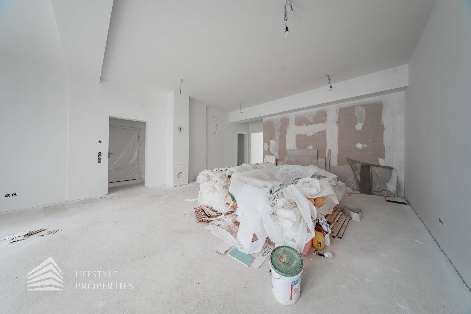 Innenraum im Rohbauzustand mit Baumaterialien und unfertigen Wänden, bereit für den Ausbau.