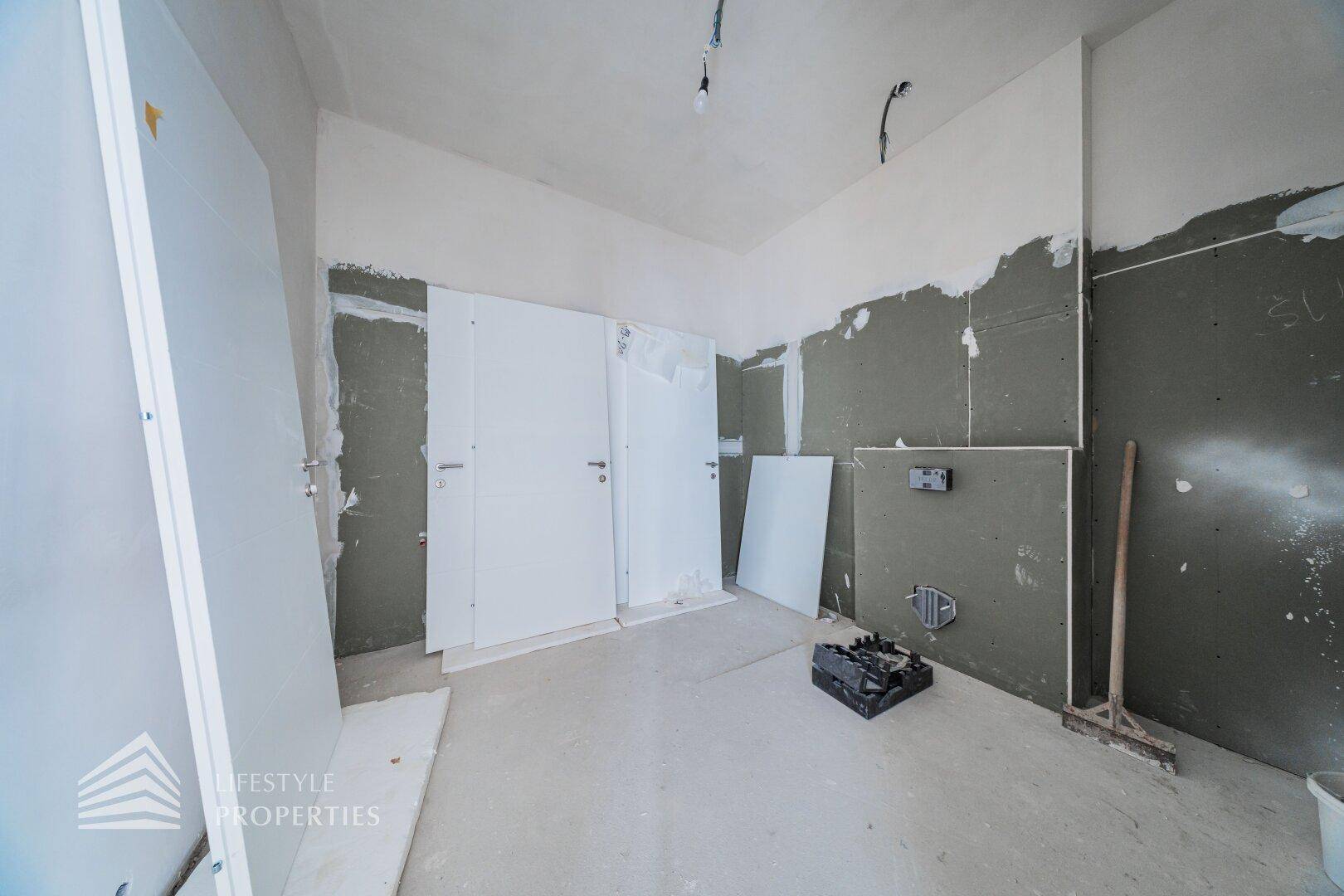 Raum im Rohbau mit Trockenbauplatten und neuen Türen, bereit zur Installation und Fertigstellung.