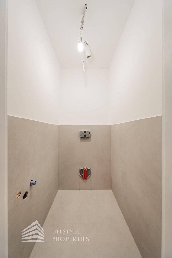 Kleiner Raum mit Fliesenboden und Anschlüssen, ideal als Gäste-WC oder Hauswirtschaftsraum.