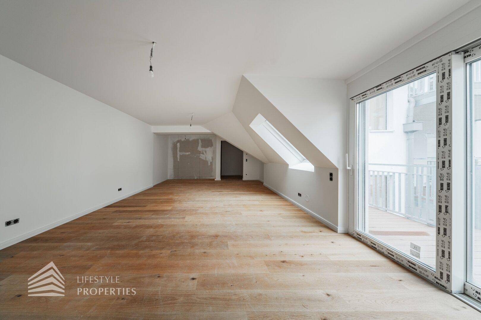 Großer, heller Raum im Dachgeschoss mit Holzboden und Zugang zu einem Außenbereich, ideal für flexible Nutzung.