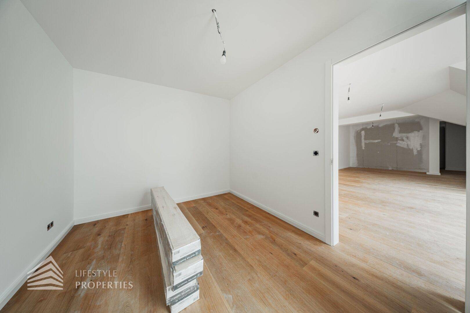 Unmöblierter Raum mit Holzboden und Zugang zu einem weiteren Zimmer, ideal für flexible Nutzungsmöglichkeiten.