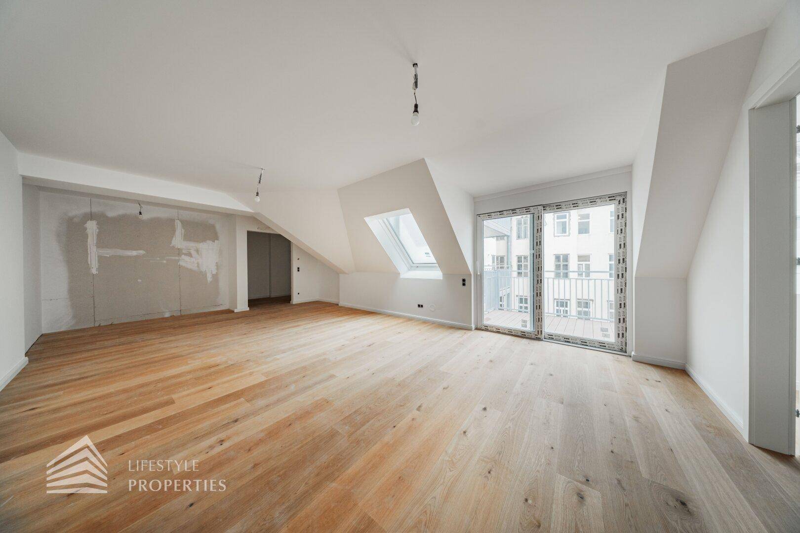 Heller, unmöblierter Raum im Dachgeschoss mit Holzboden und Dachfenster, bereit für den Innenausbau.