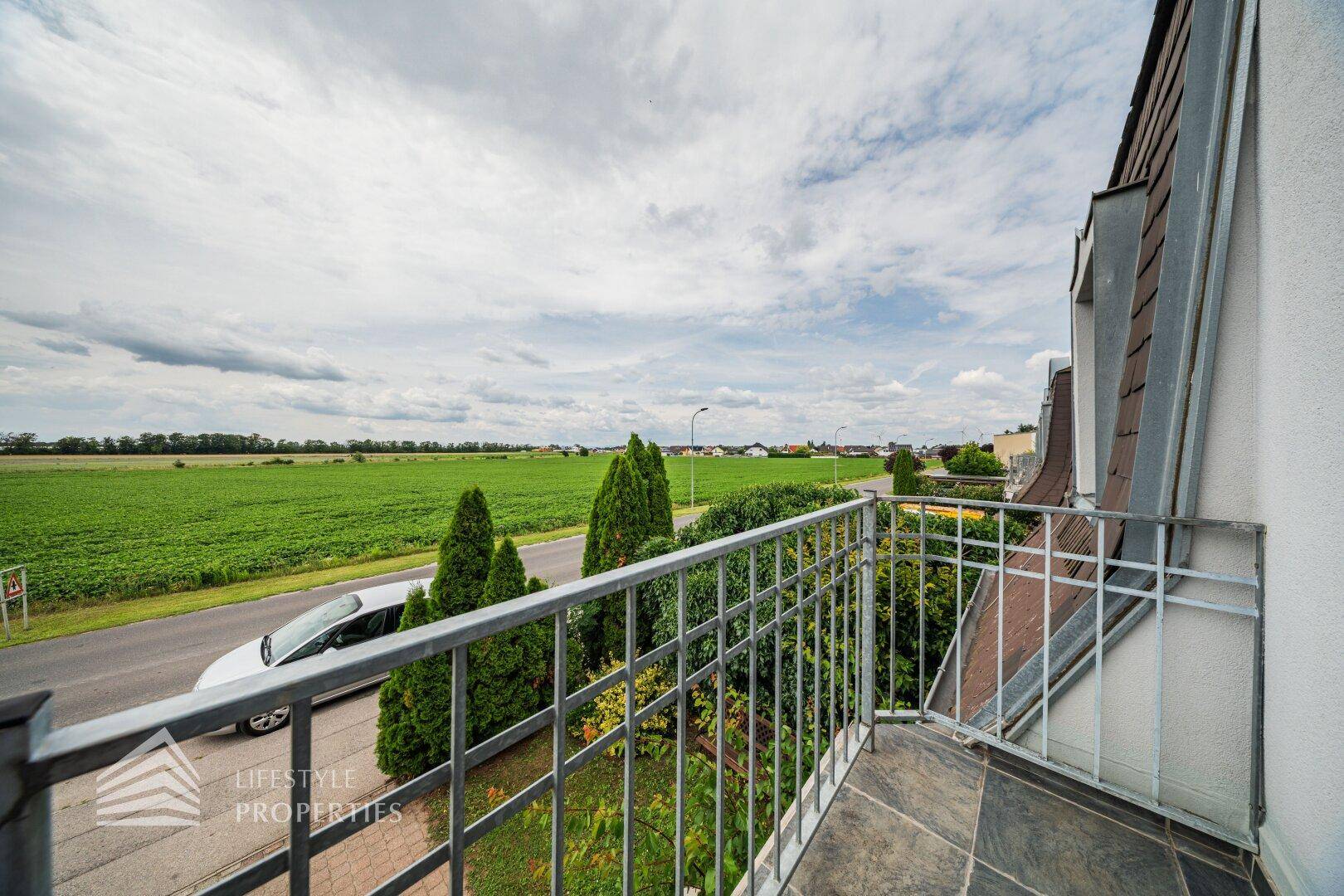 Balkon mit weitem Blick über grüne Felder und die umliegende Landschaft.
