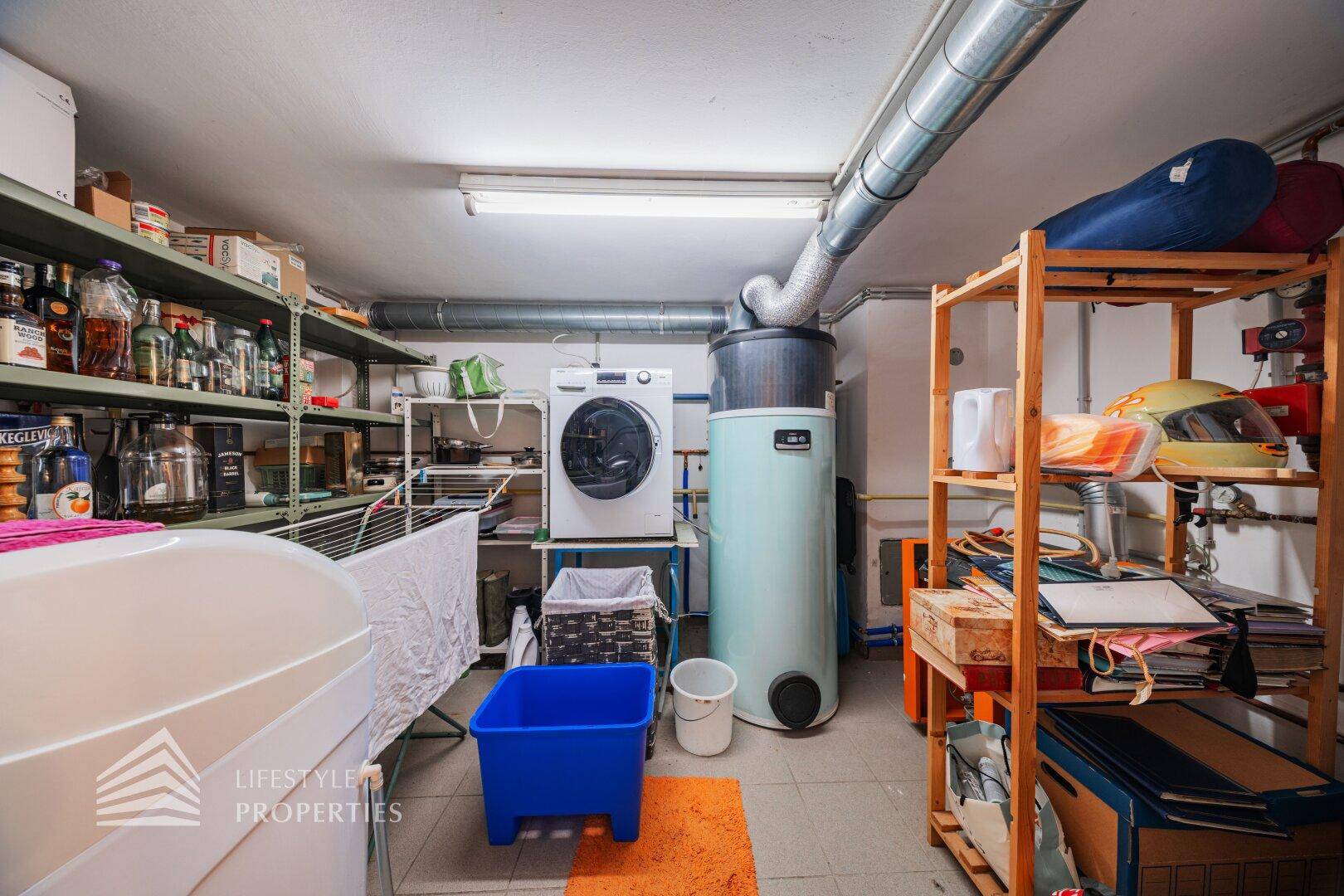 Praktischer Hauswirtschaftsraum im Keller mit Waschmaschine, Trockner und Regalen für Vorräte.