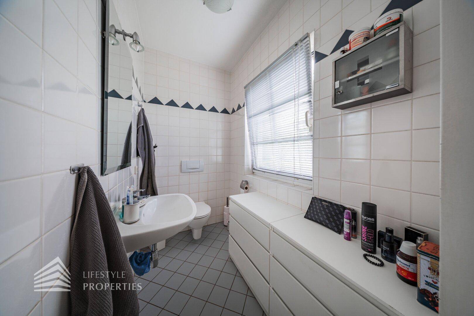 Badezimmer mit Badewanne, Waschbecken, WC und Fenster für natürliche Belüftung.