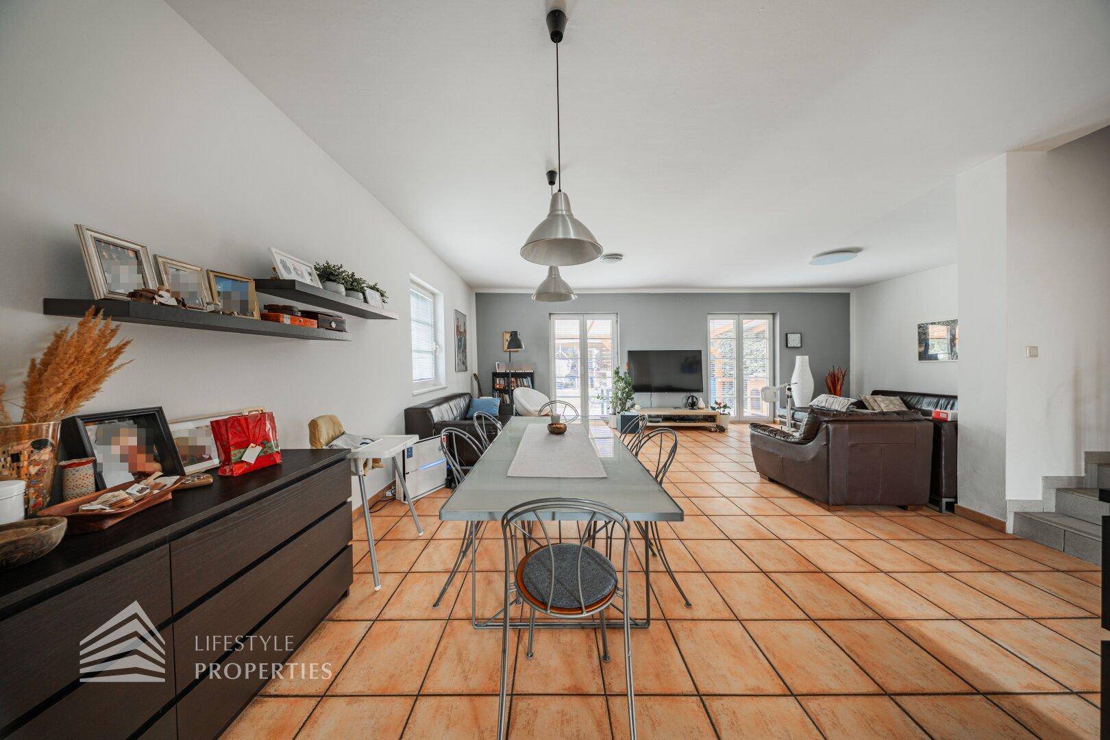 Geräumiger Wohn-Essbereich mit Terracotta-Fliesen, großem Esstisch und Zugang zur Terrasse.
