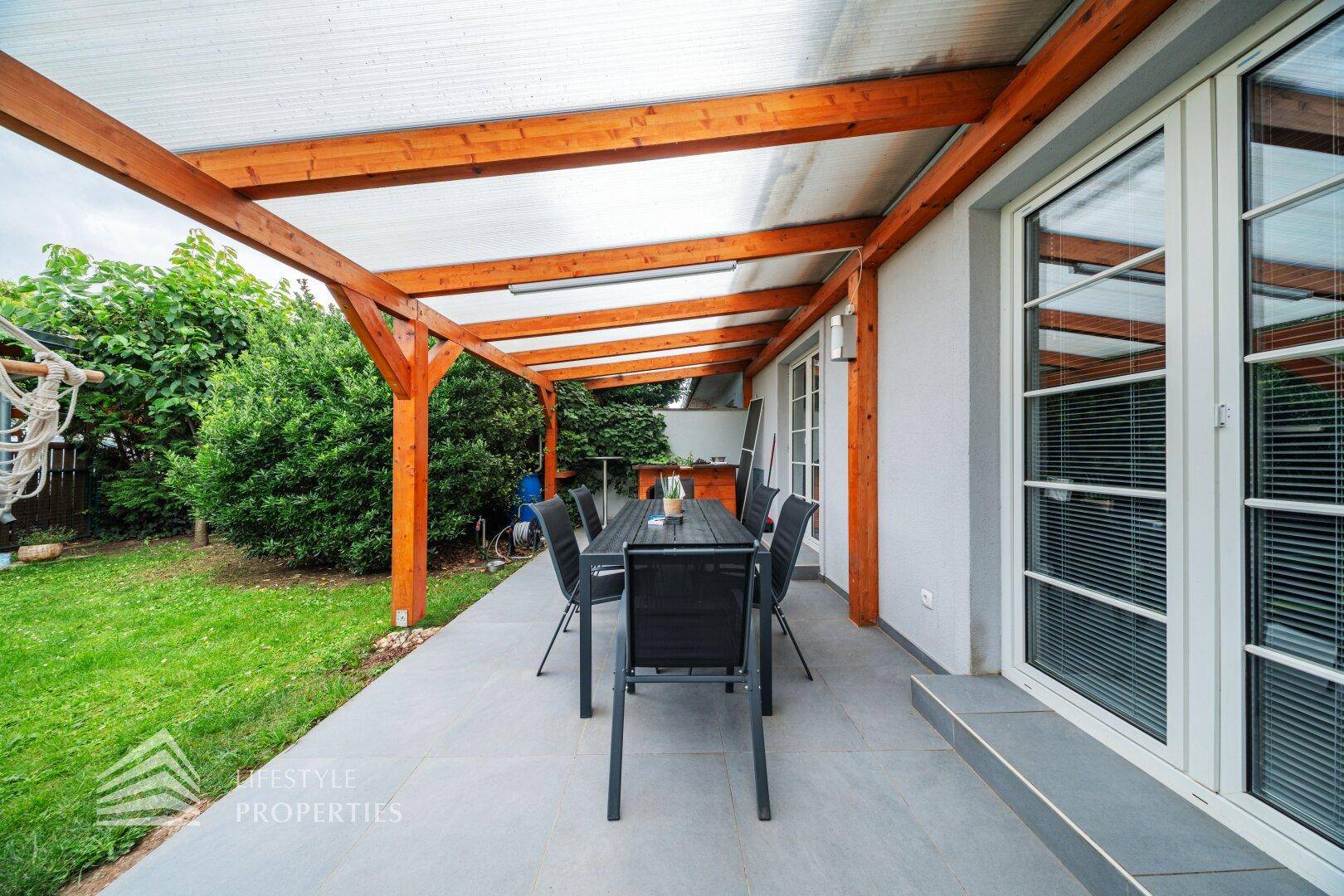 Detailansicht der überdachten Terrasse mit modernem Esstisch und Zugang zum Garten.