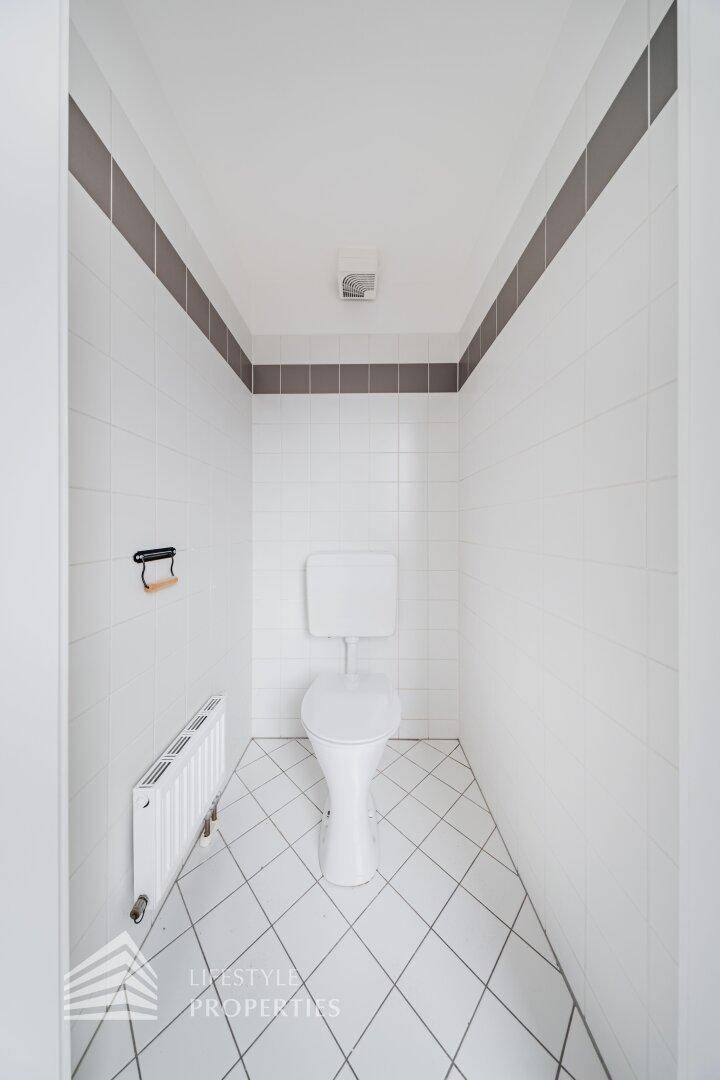 Separates WC mit weißen Fliesen und Heizkörper, funktional und sauber.
