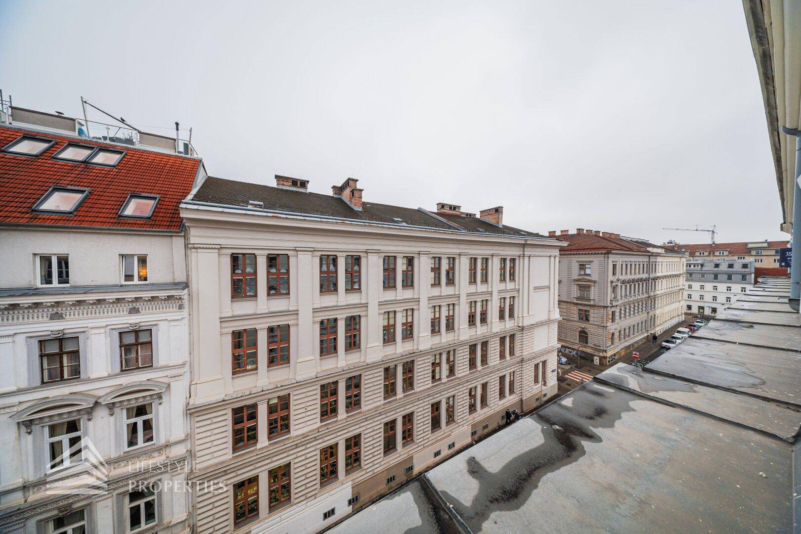Blick über die Dächer der Stadt mit angrenzenden historischen Gebäuden und einem bewölkten Himmel.