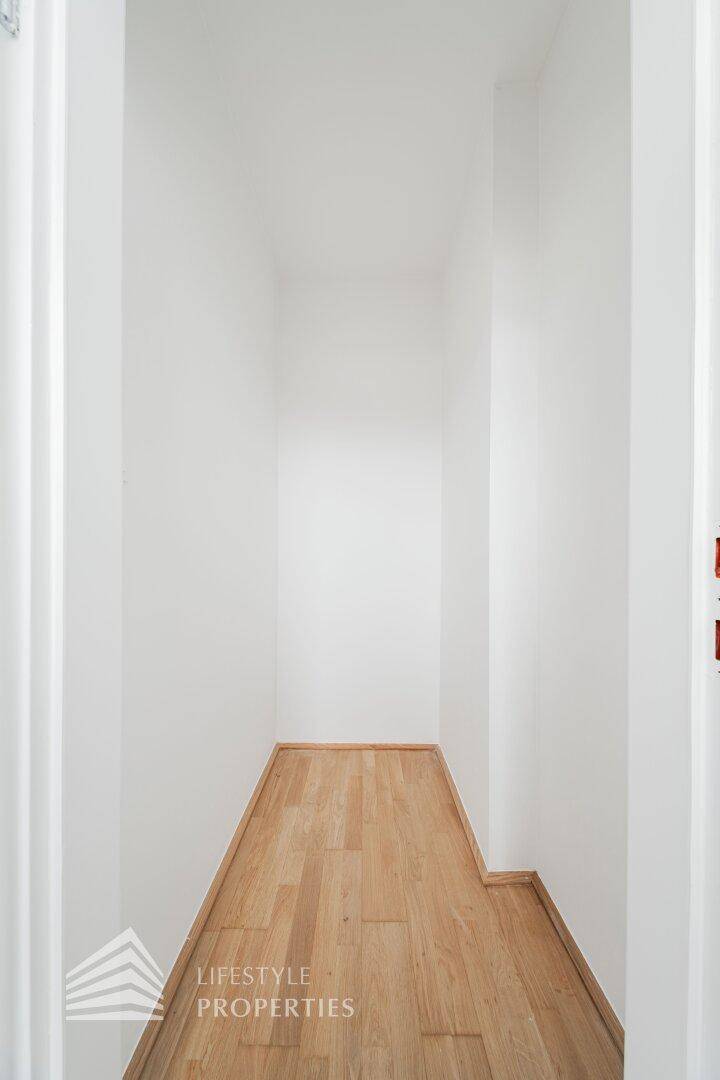 Schmaler, heller Durchgang mit Holzboden und weißen Wänden, verbindet verschiedene Bereiche der Wohnung.