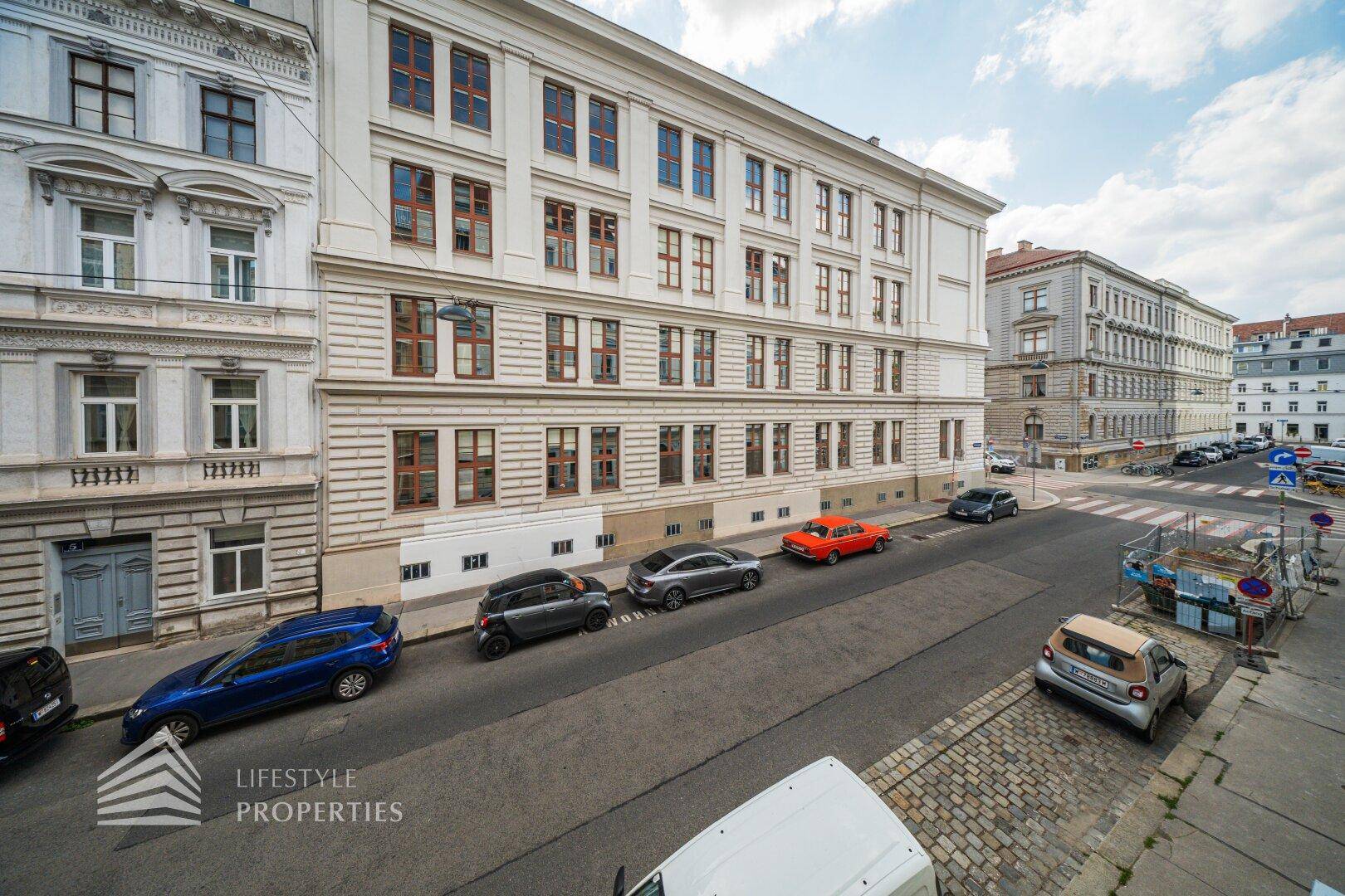 Historisches Gebäude mit vielen Fenstern und Blick auf die belebte Stadtstraße.