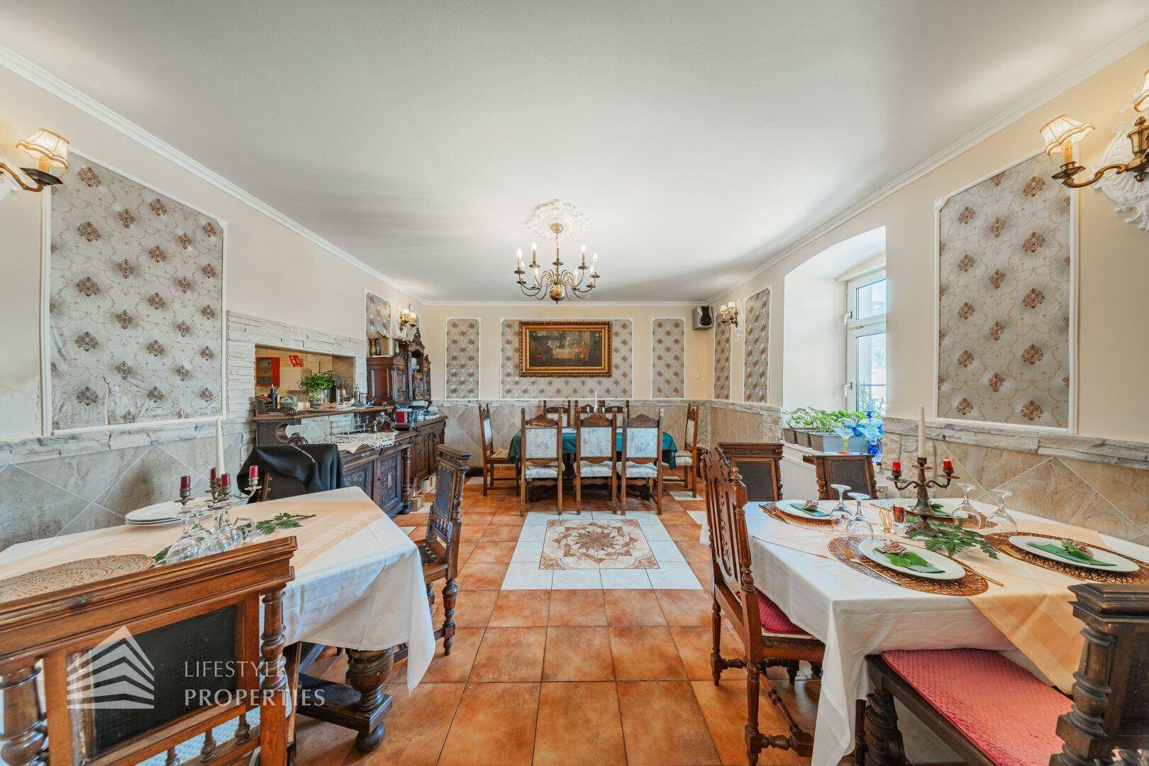 Speisesaal mit traditionellen Holzmöbeln, gedeckten Tischen und einem Buffetbereich im Hintergrund.