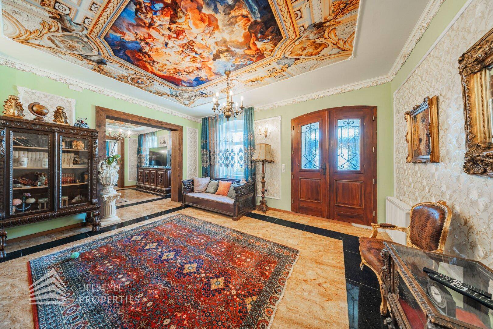 Eleganter Salon mit kunstvoller Deckenmalerei, dunklen Holztüren und luxuriöser Einrichtung.
