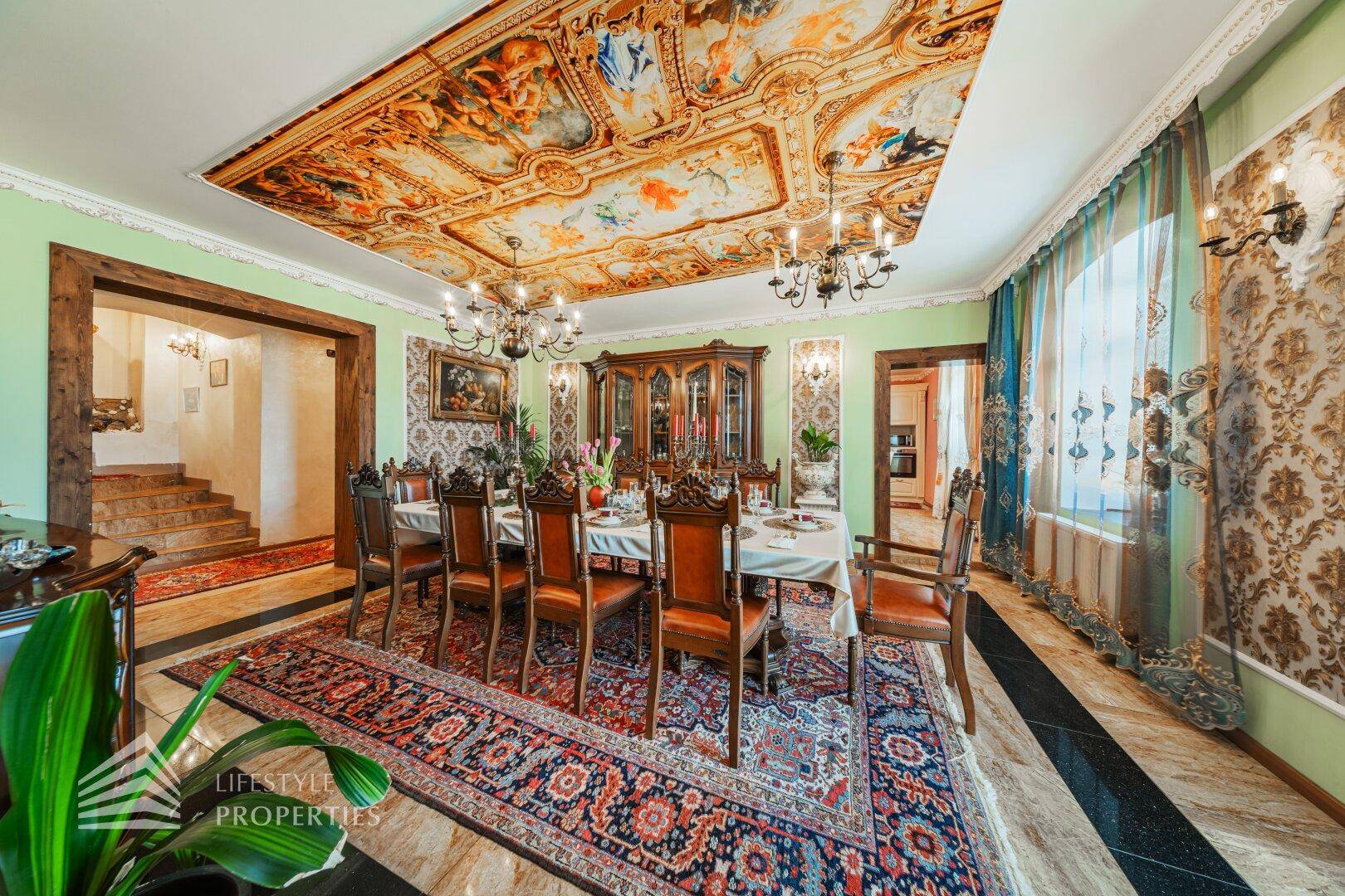 Prunkvoller Speisesaal mit langem Esstisch, Kronleuchtern und dem beeindruckenden Deckengemälde.