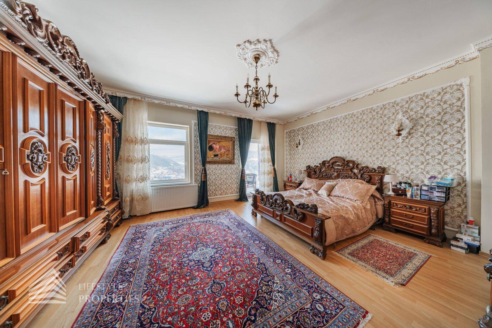 Geräumiges Schlafzimmer mit opulentem Holzbett, passendem Kleiderschrank und gemusterter Tapete.