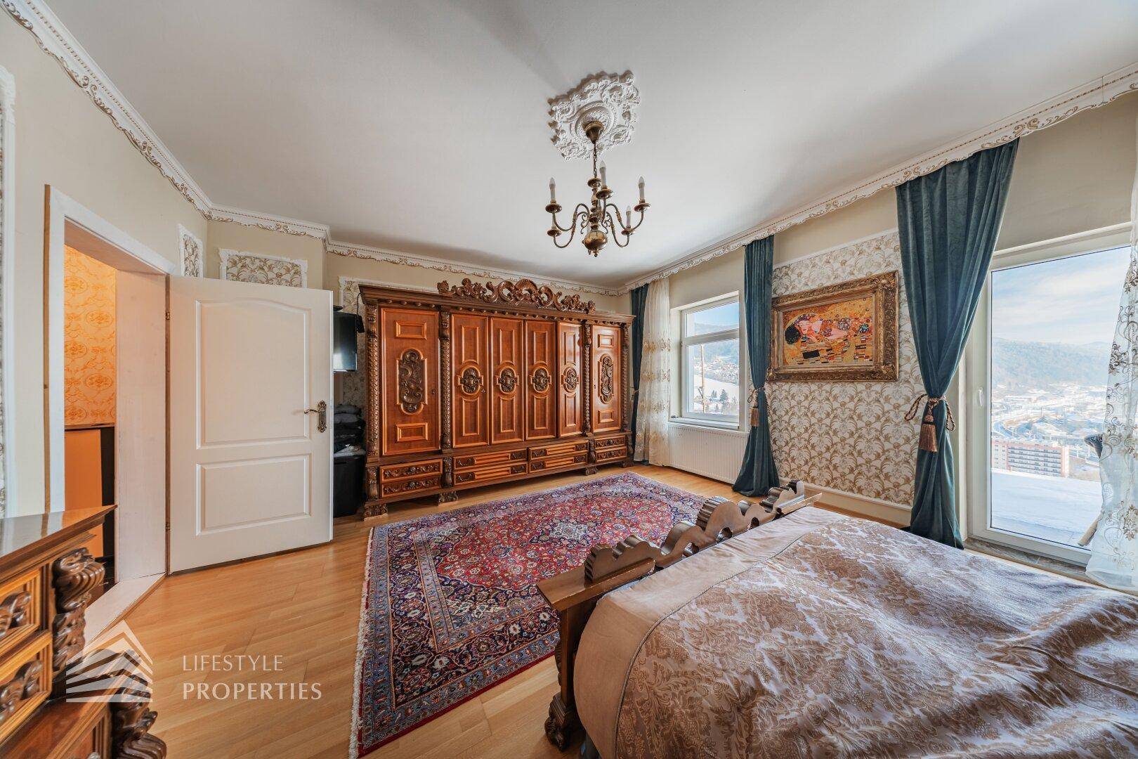 Schlafzimmer mit traditionellen Möbeln, Holzboden und einem Fenster mit Blick auf die Landschaft.