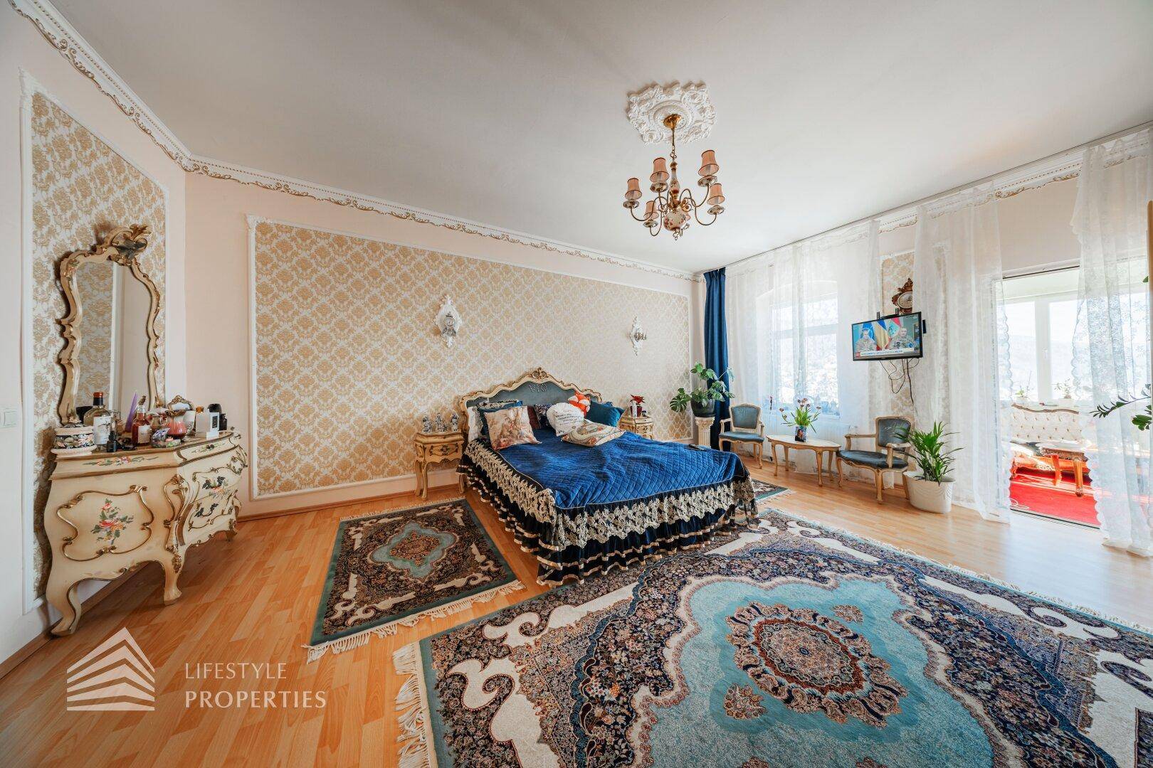 Schlafzimmer mit traditionellem Schminktisch, Spiegel und Fenster, das viel Tageslicht hereinlässt.