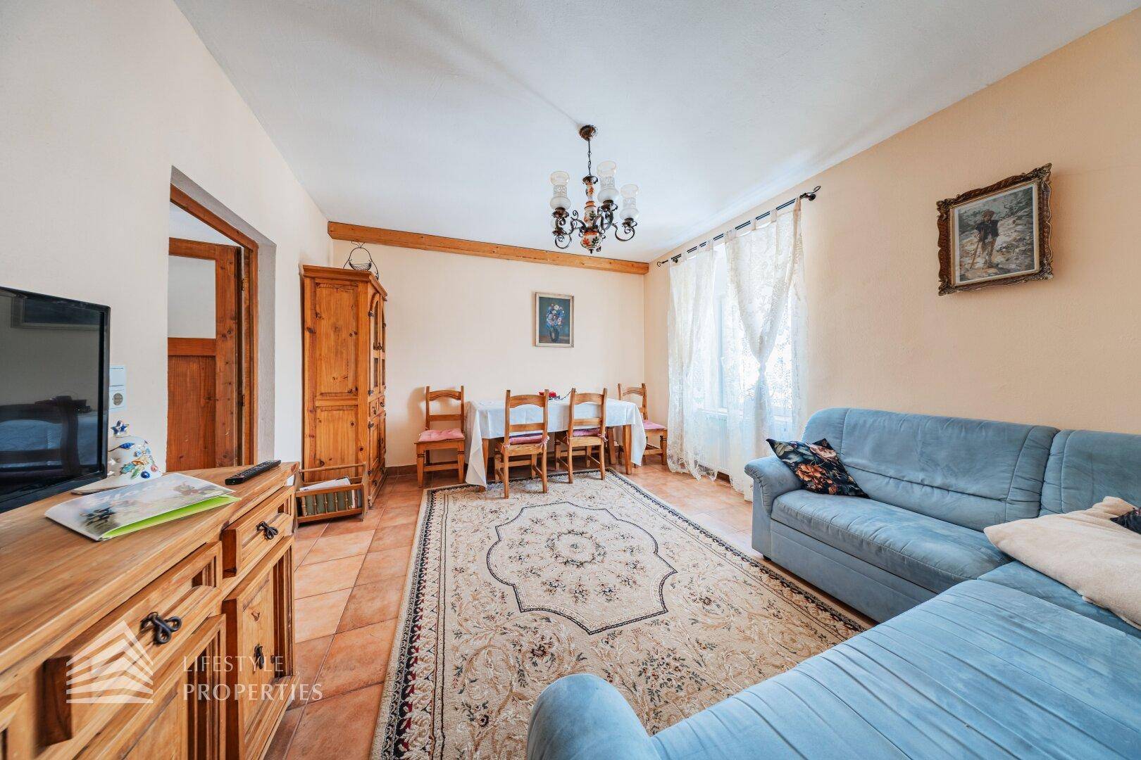 Geräumiger Wohn- und Essbereich mit Esstisch, blauer Couch und traditionellen Holzmöbeln.