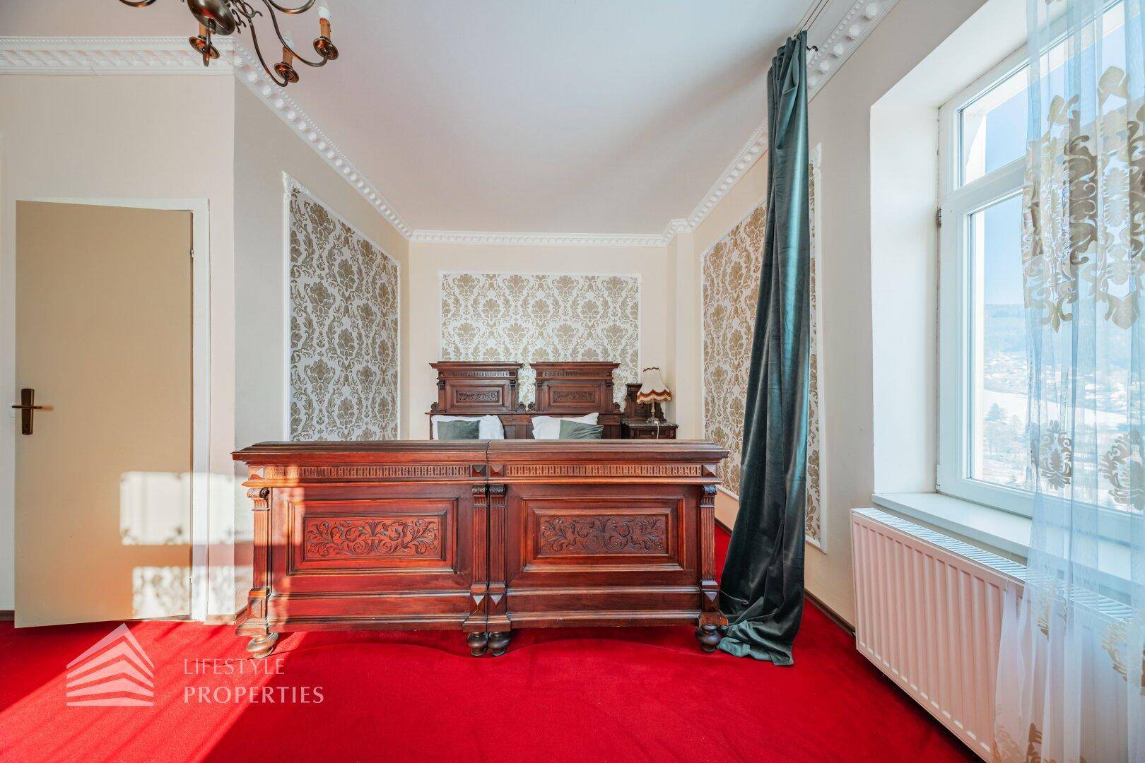 Detailansicht eines Bettes im klassischen Schlafzimmer mit Fenster und Heizkörper darunter.
