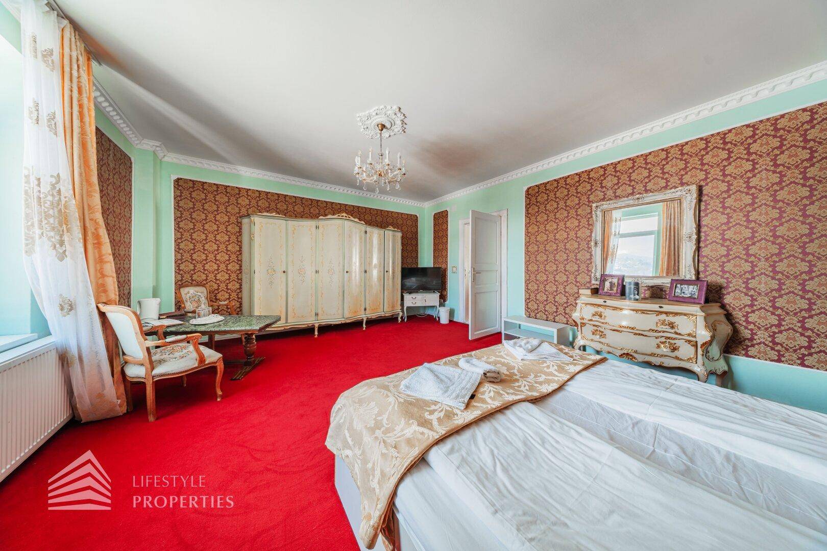 Großes Schlafzimmer mit Doppelbett, weißem Kleiderschrank und Kommode, klassisch und hell eingerichtet.