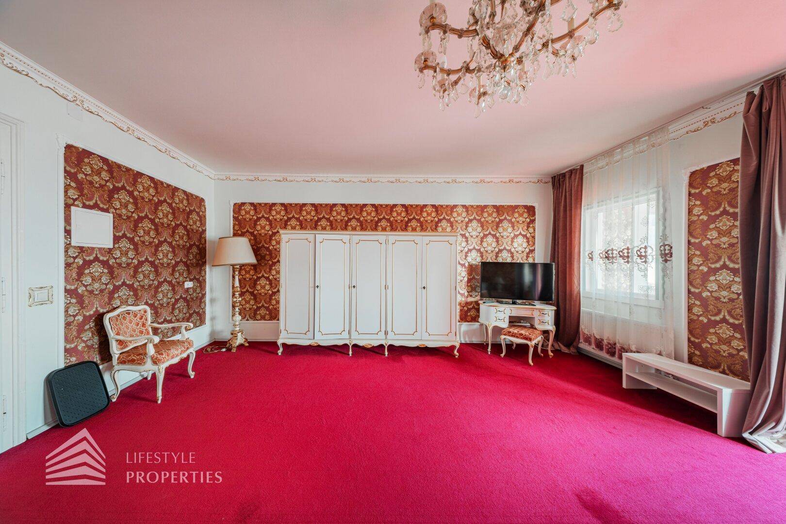Großes Schlafzimmer mit rotem Teppich, weißem Kleiderschrank und klassischer Einrichtung.
