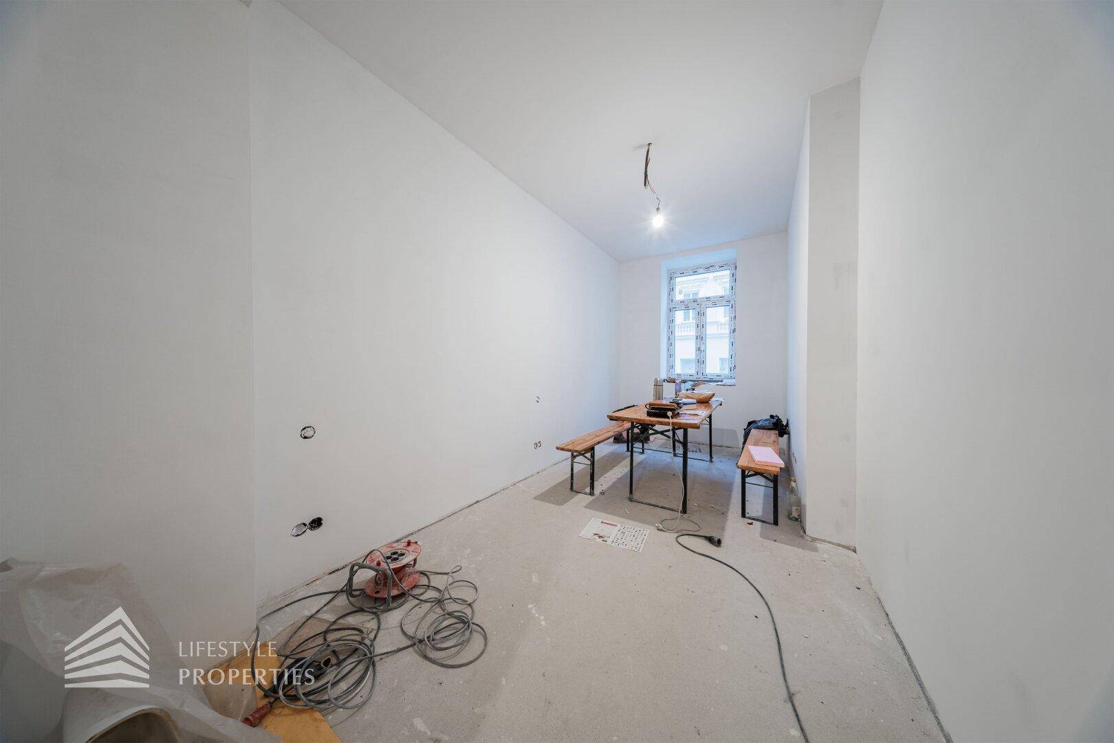 Heller Raum im Rohbau mit einem Fenster und provisorischer Arbeitsfläche, bereit für den Innenausbau.