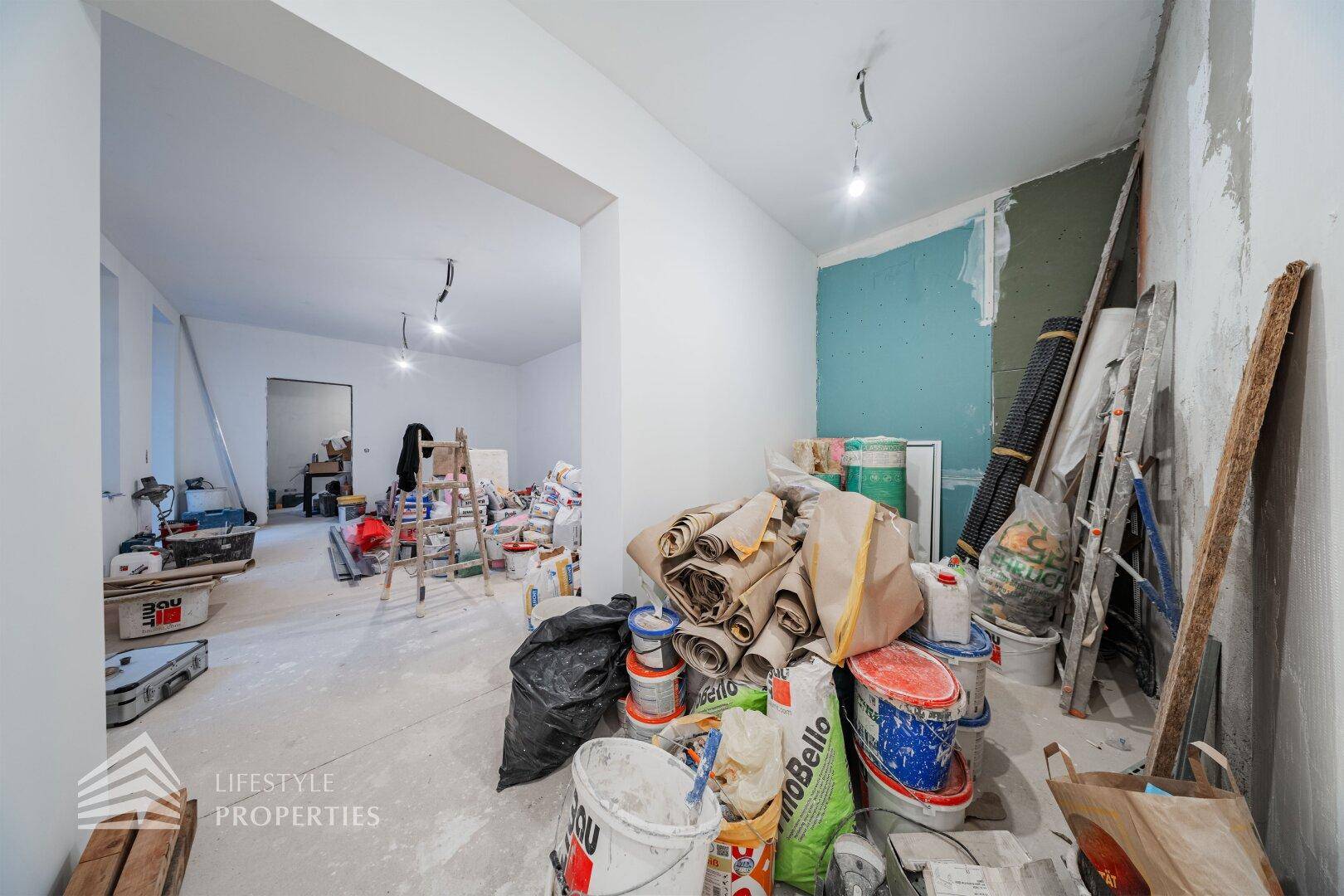 Innenraum im Rohbau mit einer Vielzahl von Baumaterialien und Werkzeugen, bereit für den Ausbau.