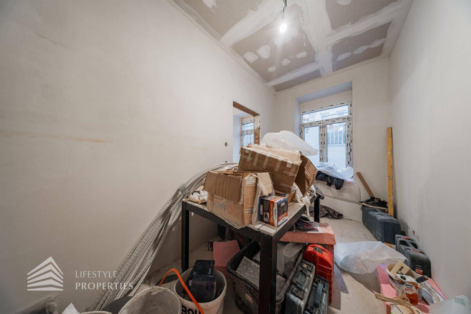 Raum im Rohbau mit sichtbaren Deckenkonstruktionen und Baumaterialien, bereit für den Innenausbau.