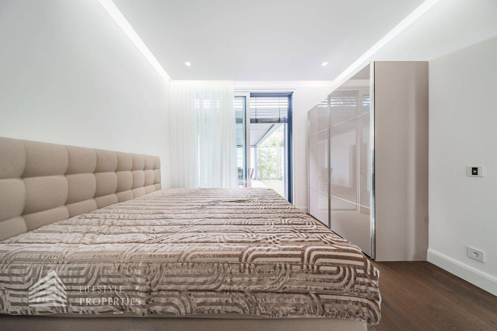Helles Schlafzimmer mit großem Bett, Einbauschrank und Zugang zu einem Balkon.