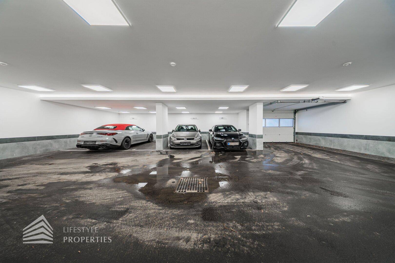 Breite Tiefgarage mit ausreichend Platz für mehrere Fahrzeuge und Rolltor.