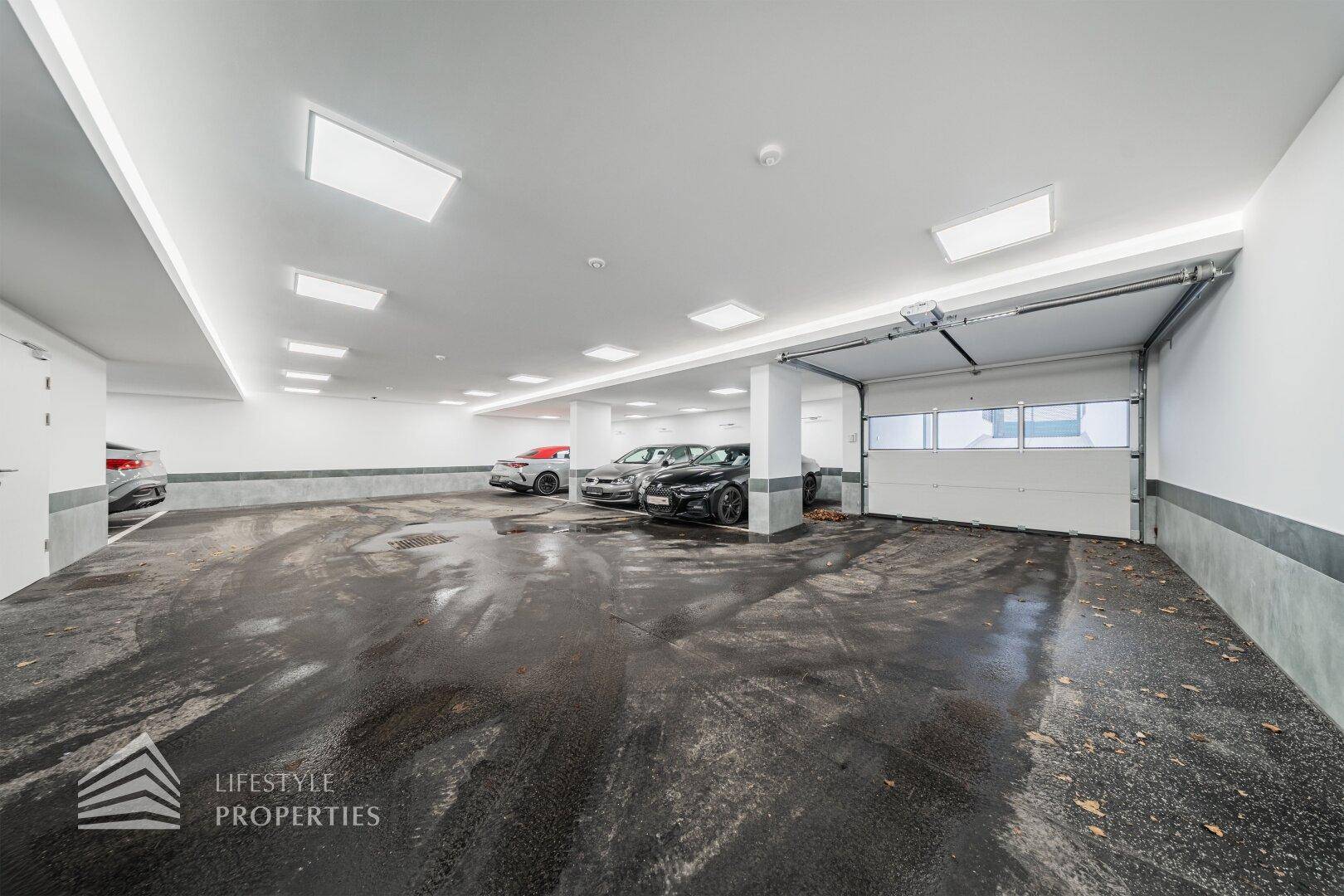 Tiefgarage mit mehreren Stellplätzen und Zugang über ein breites Garagentor.