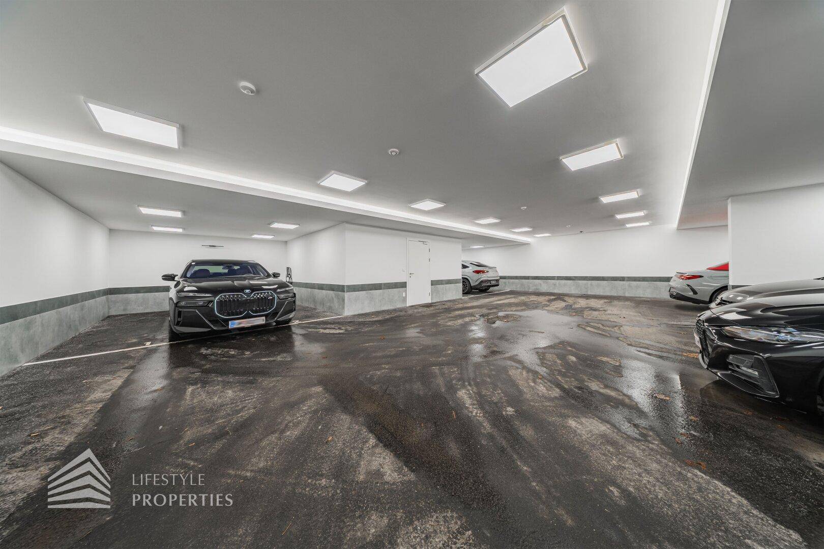 Geräumige Tiefgarage mit mehreren Stellplätzen und heller Beleuchtung.