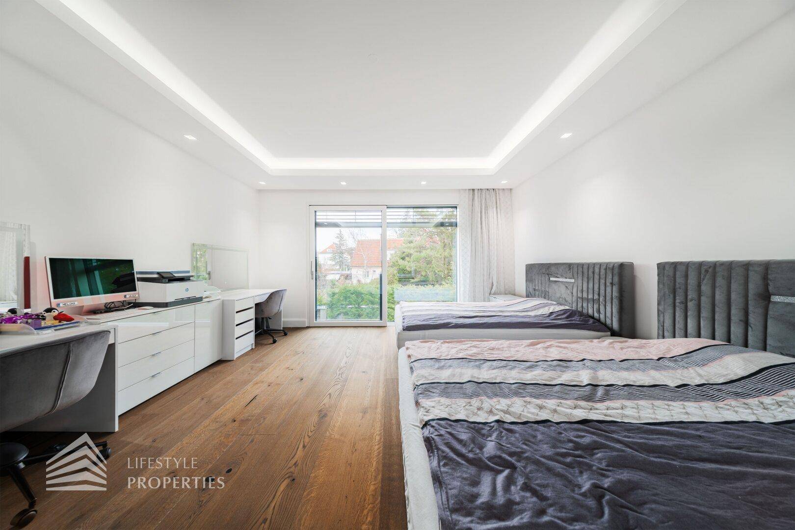 Kinder- oder Gästezimmer mit zwei Betten, Schreibtisch und Holzboden, hell und funktional eingerichtet.