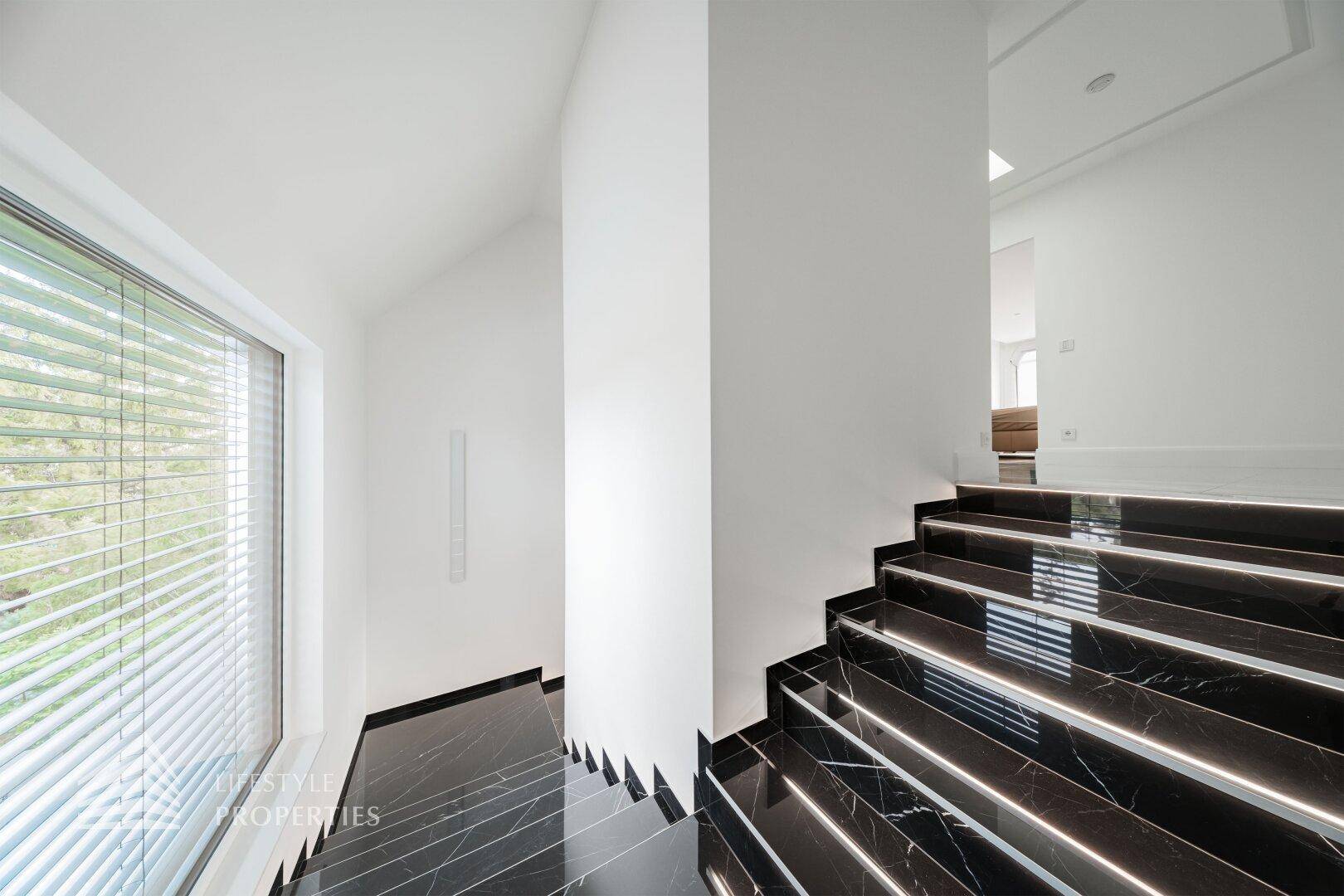 Elegante Treppe mit schwarzem Marmor und integrierter Beleuchtung, die die Etagen verbindet.