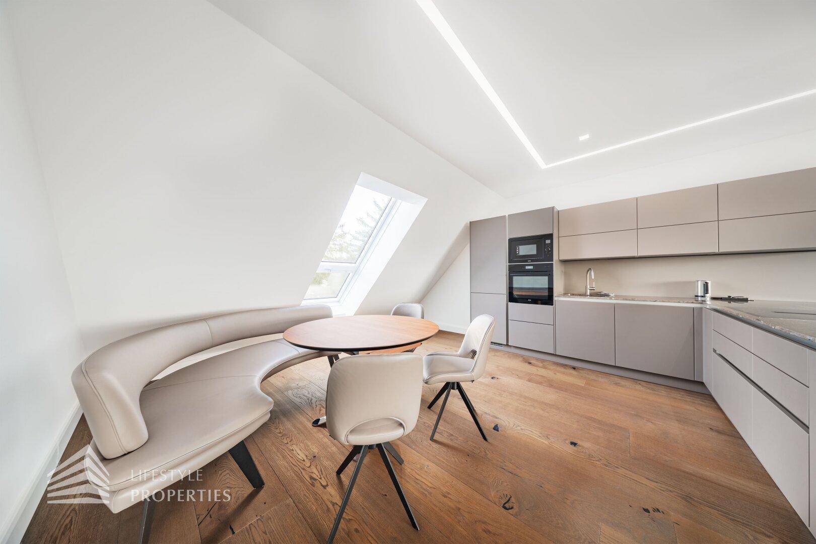 Moderne Küche mit Essbereich im Dachgeschoss, Holzboden und Dachfenster für natürliches Licht.