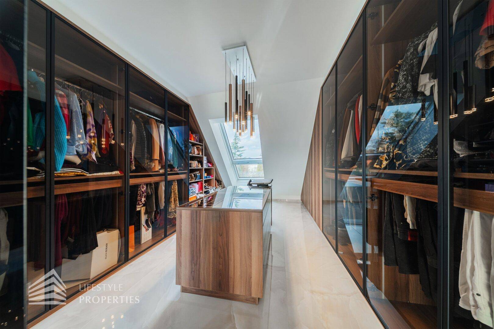 Geräumiger begehbarer Kleiderschrank mit eleganten Glasfronten und viel Stauraum.