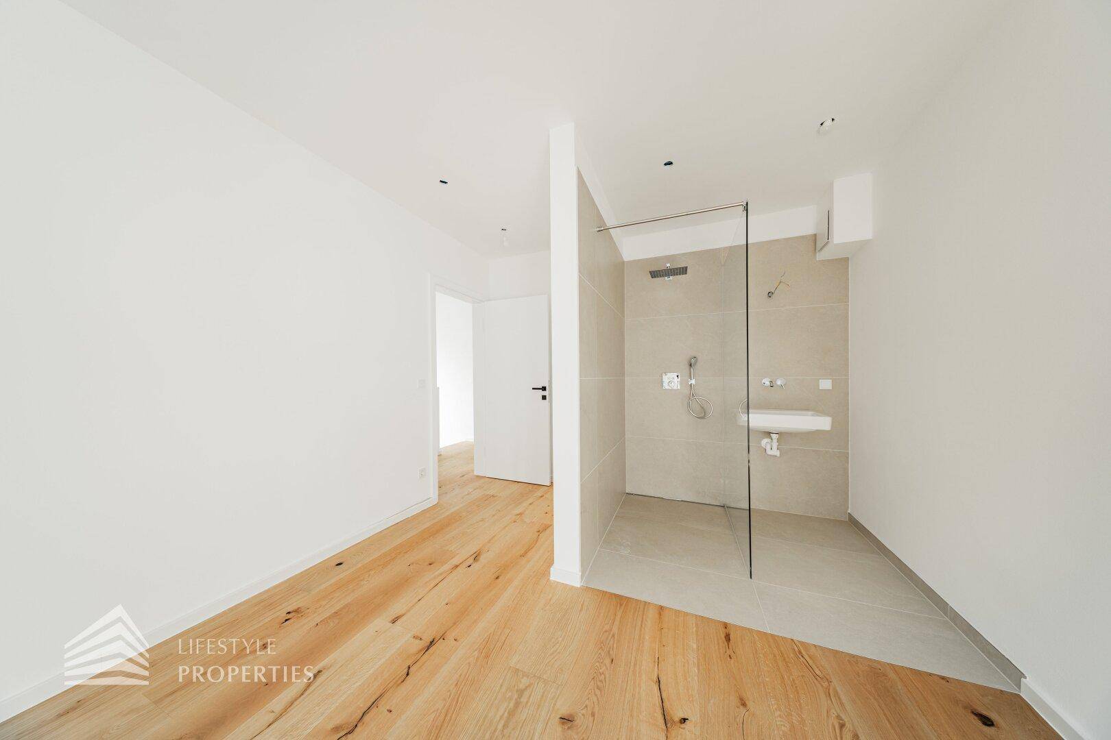 Schlafzimmer mit Holzdielenboden und offenem Duschbereich, der modernes Design betont.